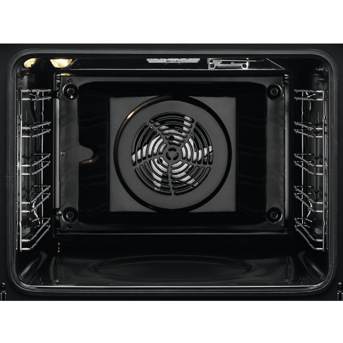 Interior de un horno negro con rejillas metálicas y un ventilador. La luz ilumina el interior.