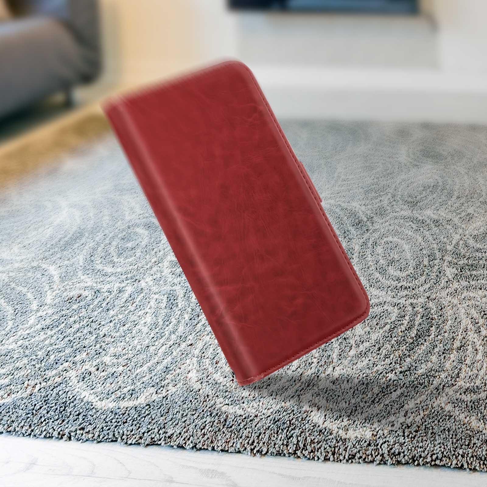 Eine rote Leder-Handyhülle fällt über einen gemusterten Teppich. Die Hülle ist leicht schräg und wirft einen Schatten.