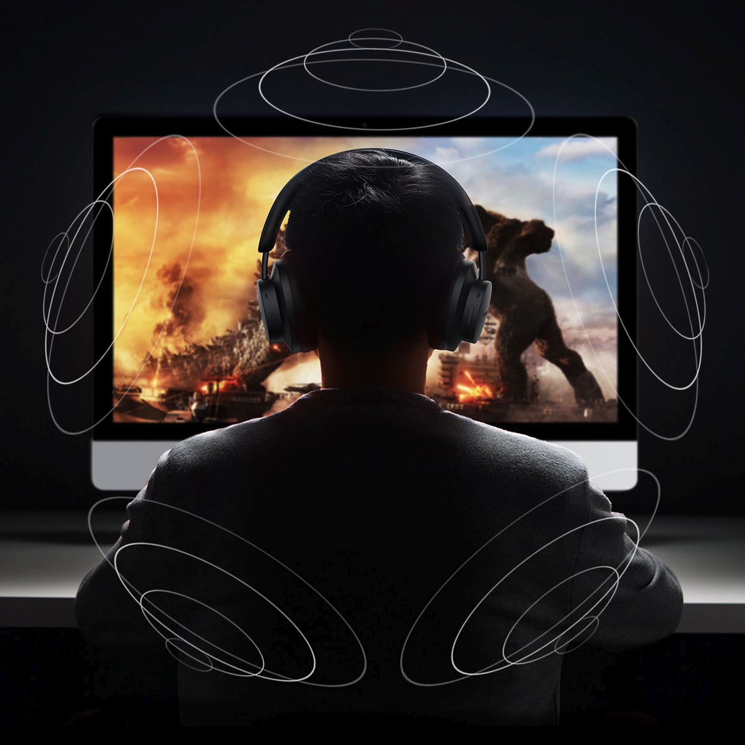 Eine Person mit Kopfhörern schaut auf einen Computer. Der Bildschirm zeigt eine feurige Szene.