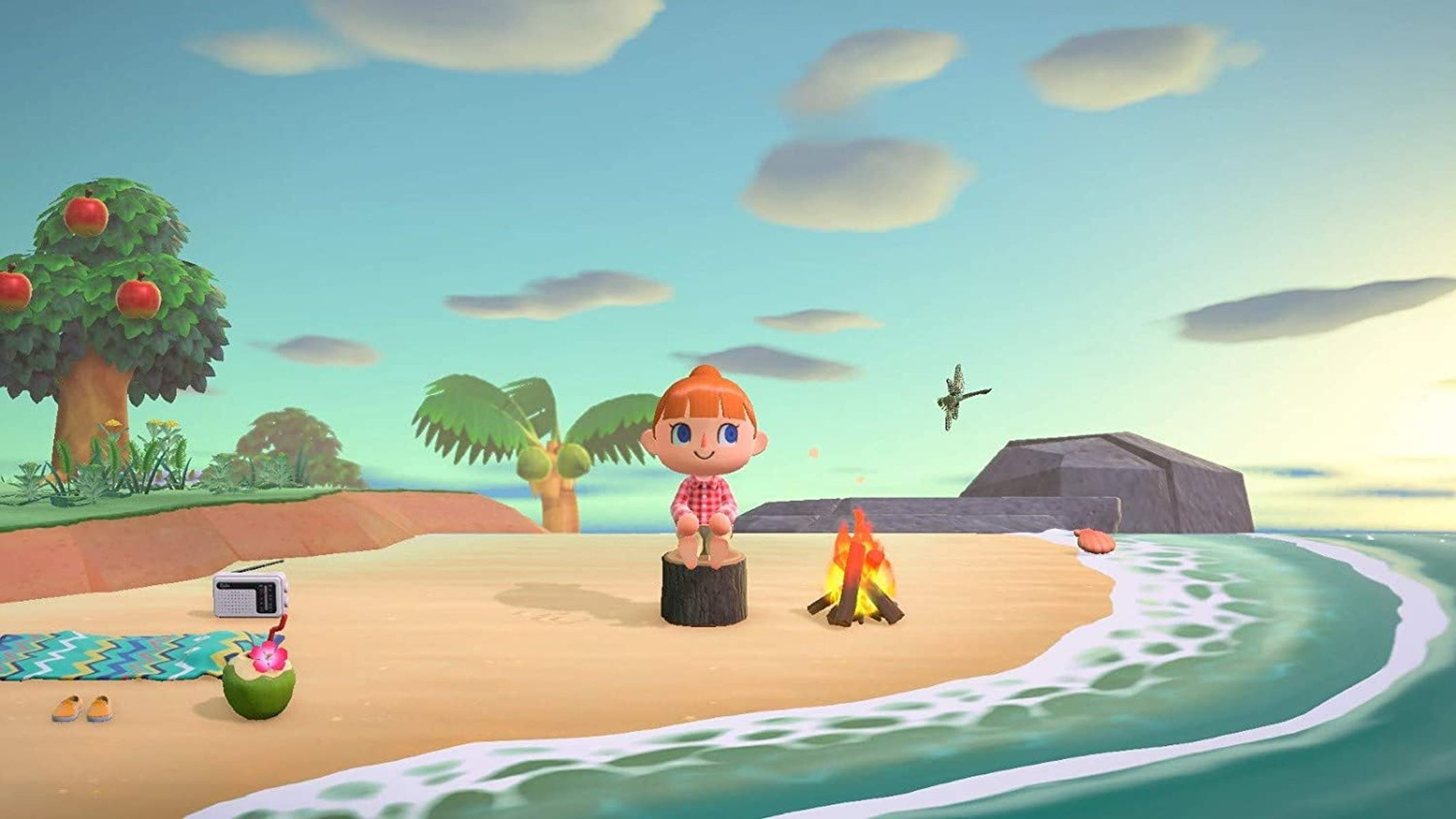 Een strandscène uit Animal Crossing. Een persoon zit op een boomstronk, bij een vuur.
