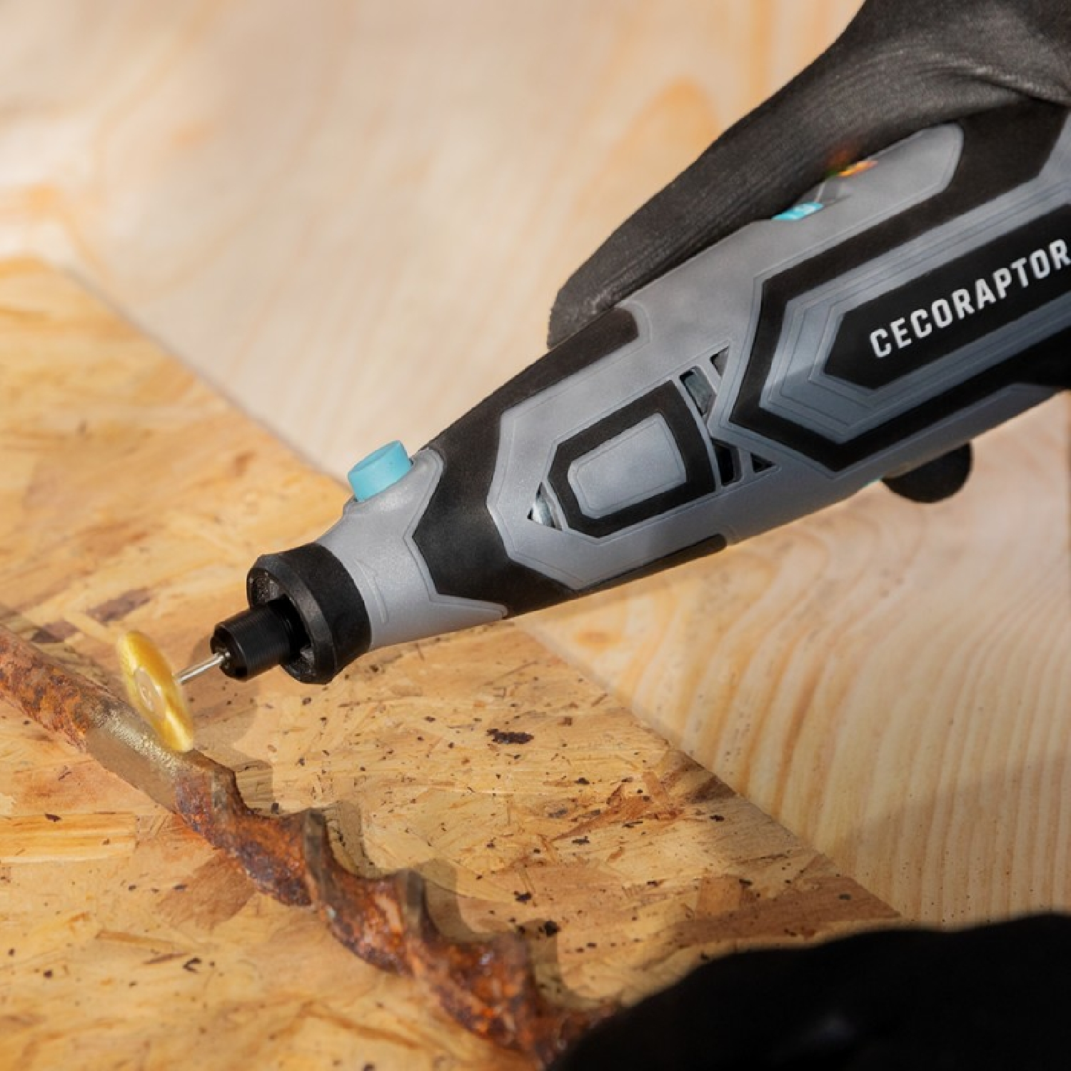 Una persona usando una herramienta eléctrica gris y negra sobre una superficie de madera, moliendo una pieza de metal oxidado.