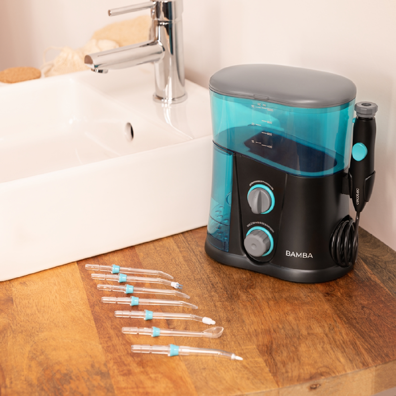 Een zwart en blauwgroen waterflosapparaat met accessoires op een houten oppervlak.