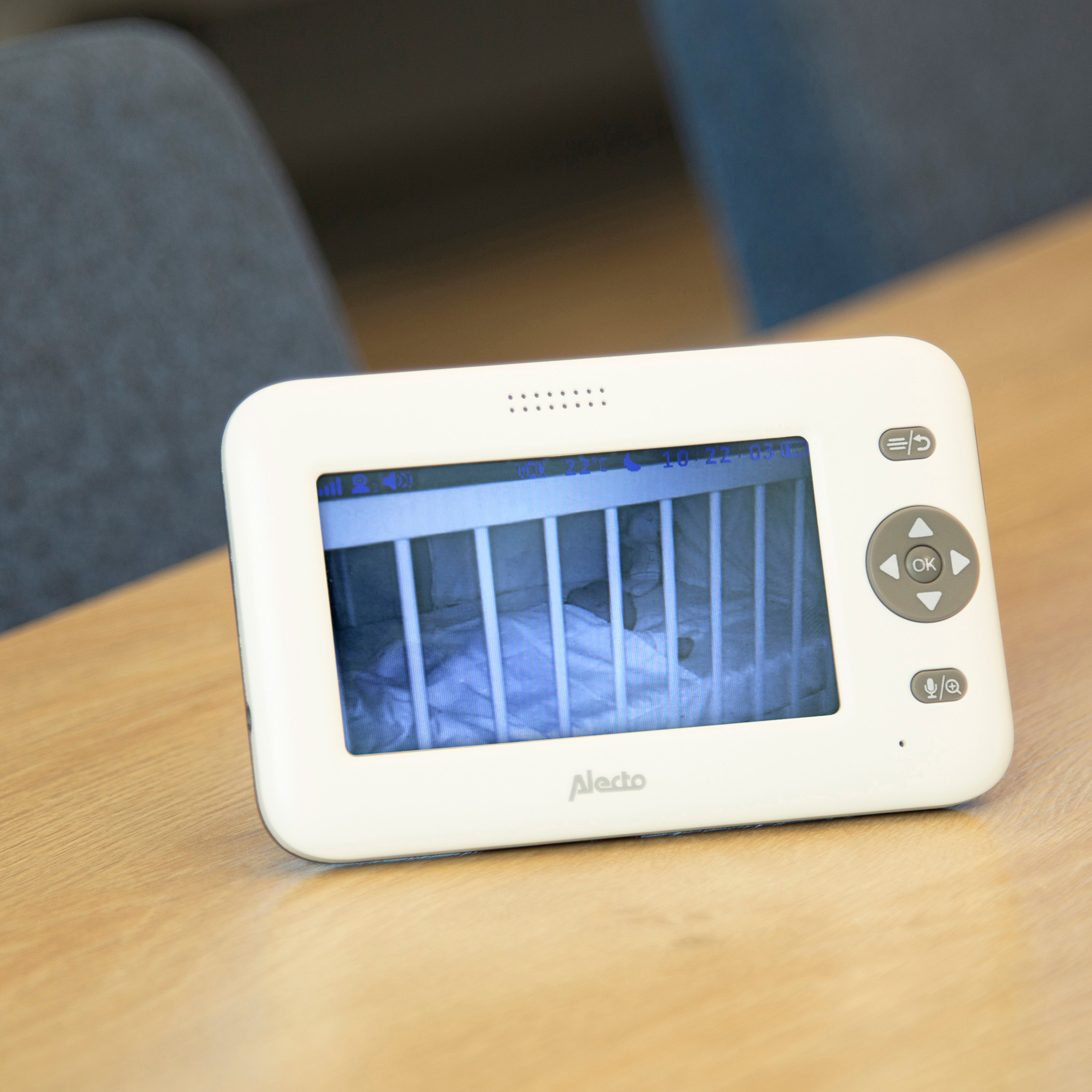 Babyphone zeigt ein Baby in einem Kinderbett auf einem Holztisch.
