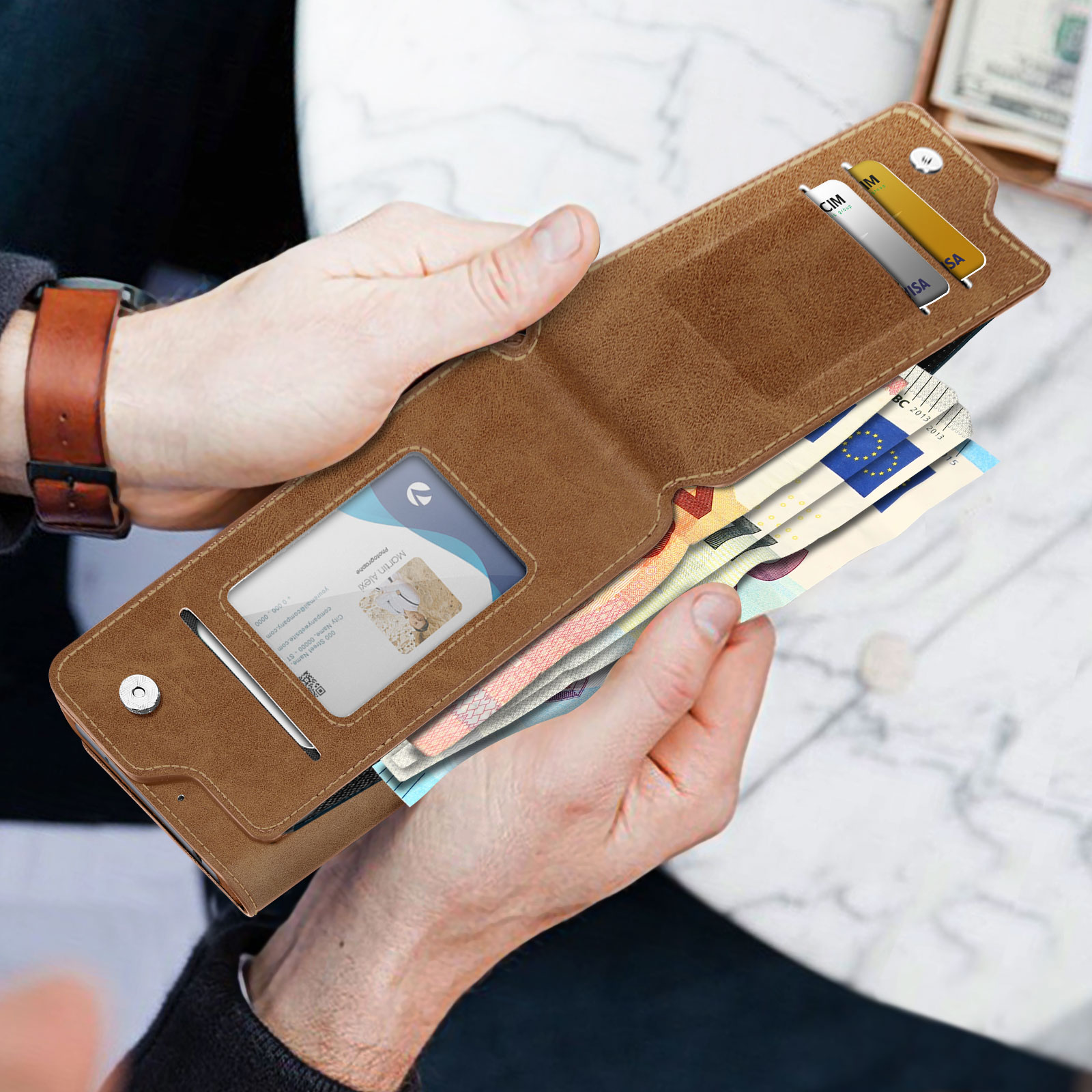 Una persona che tiene in mano un portafoglio marrone, con carte e denaro visibili.