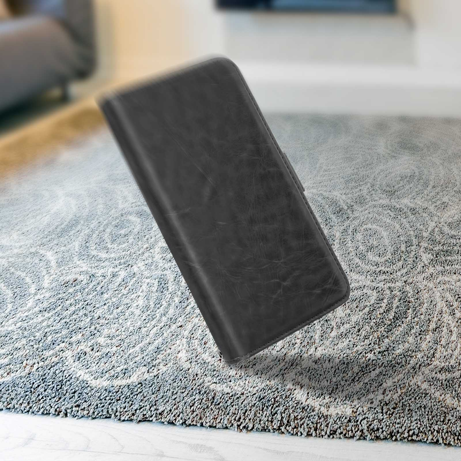 Una custodia per telefono nera cade su un tappeto fantasia. La custodia è simile alla pelle con chiusura magnetica.