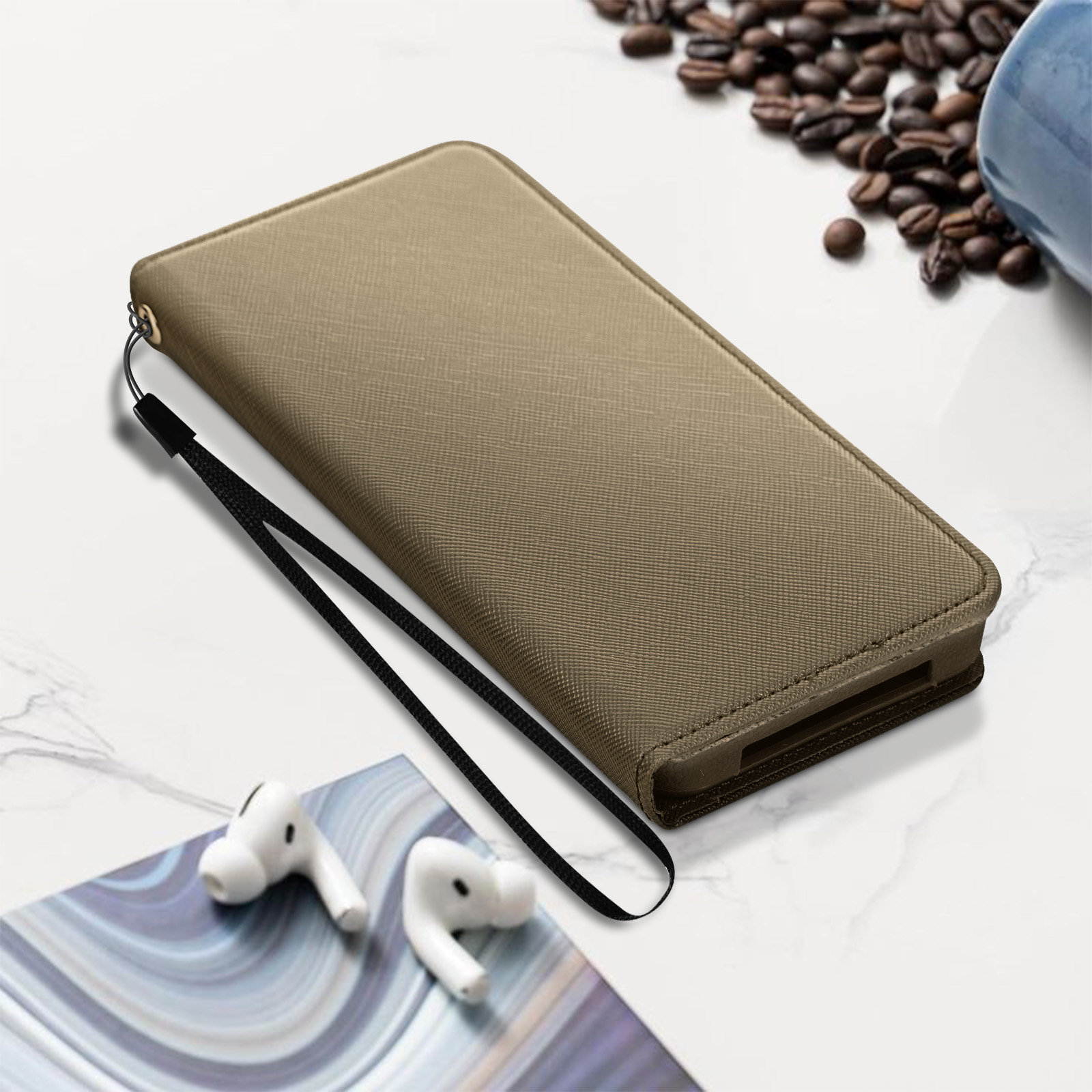 Una custodia per telefono color beige con cinturino da polso su una superficie di marmo, con auricolari e chicchi di caffè.