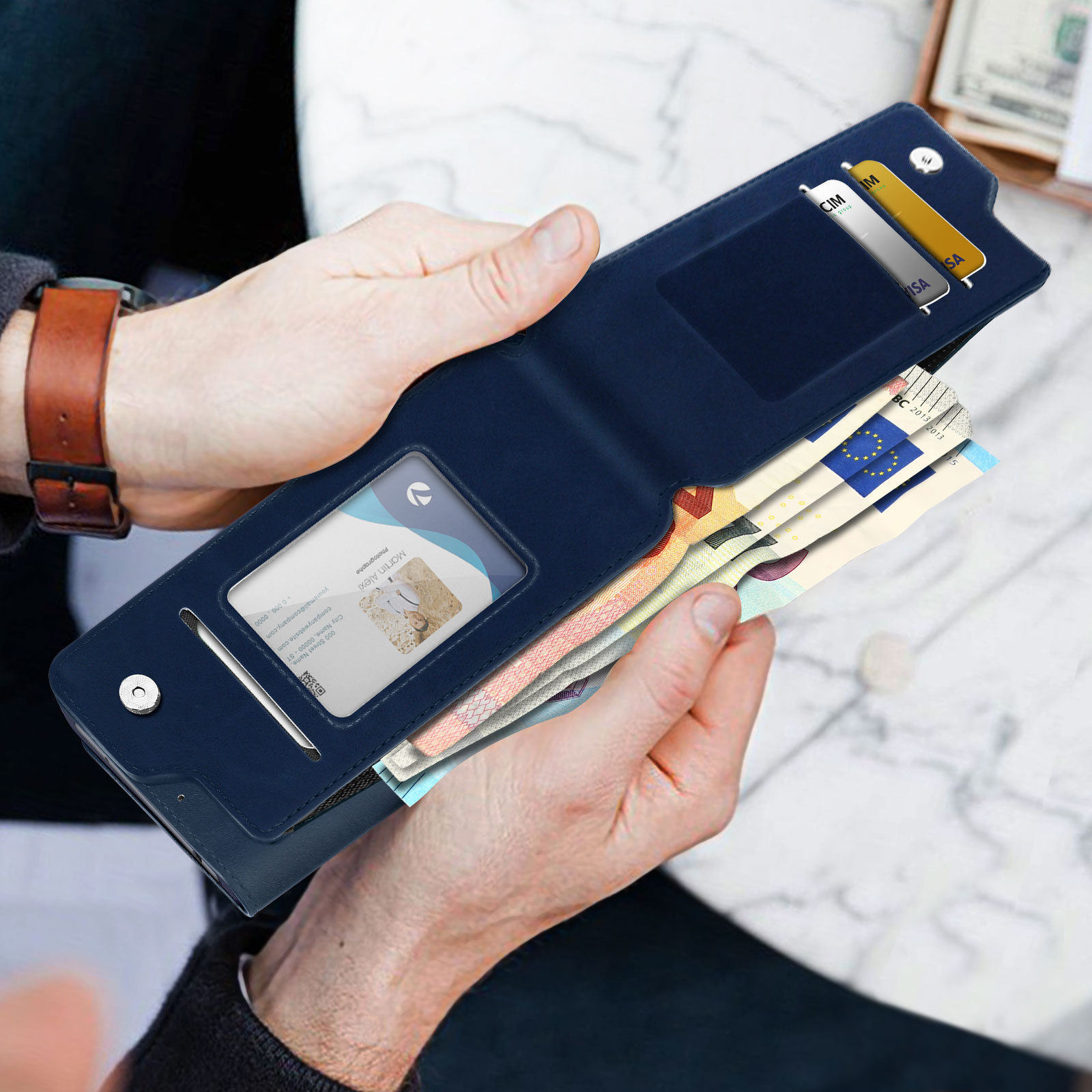 Le mani di una persona che tiene un portafoglio blu con contanti e carte.