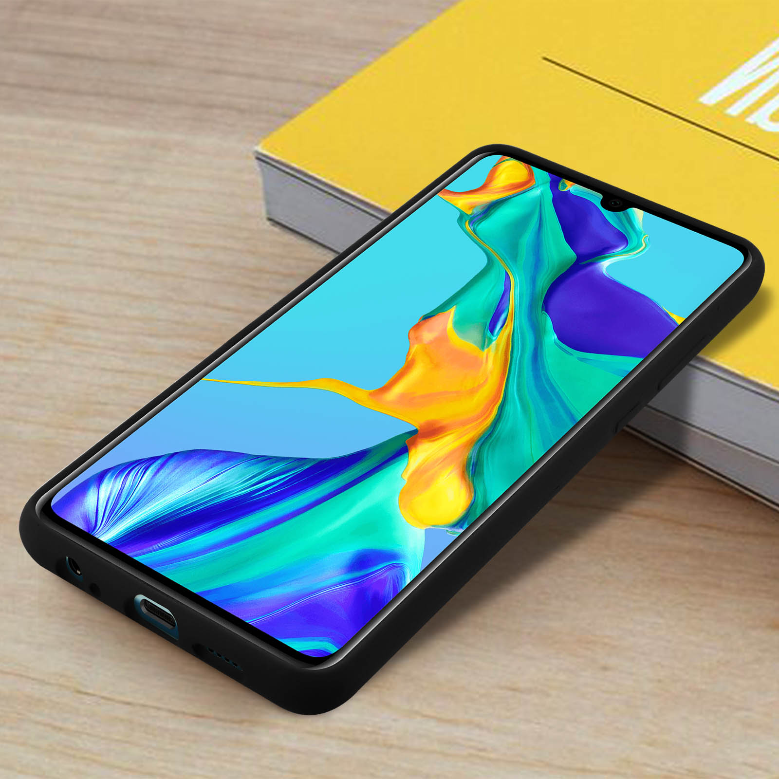 Ein schwarzes Telefon in einer Hülle, mit farbenfrohem Hintergrund auf einem Holztisch.