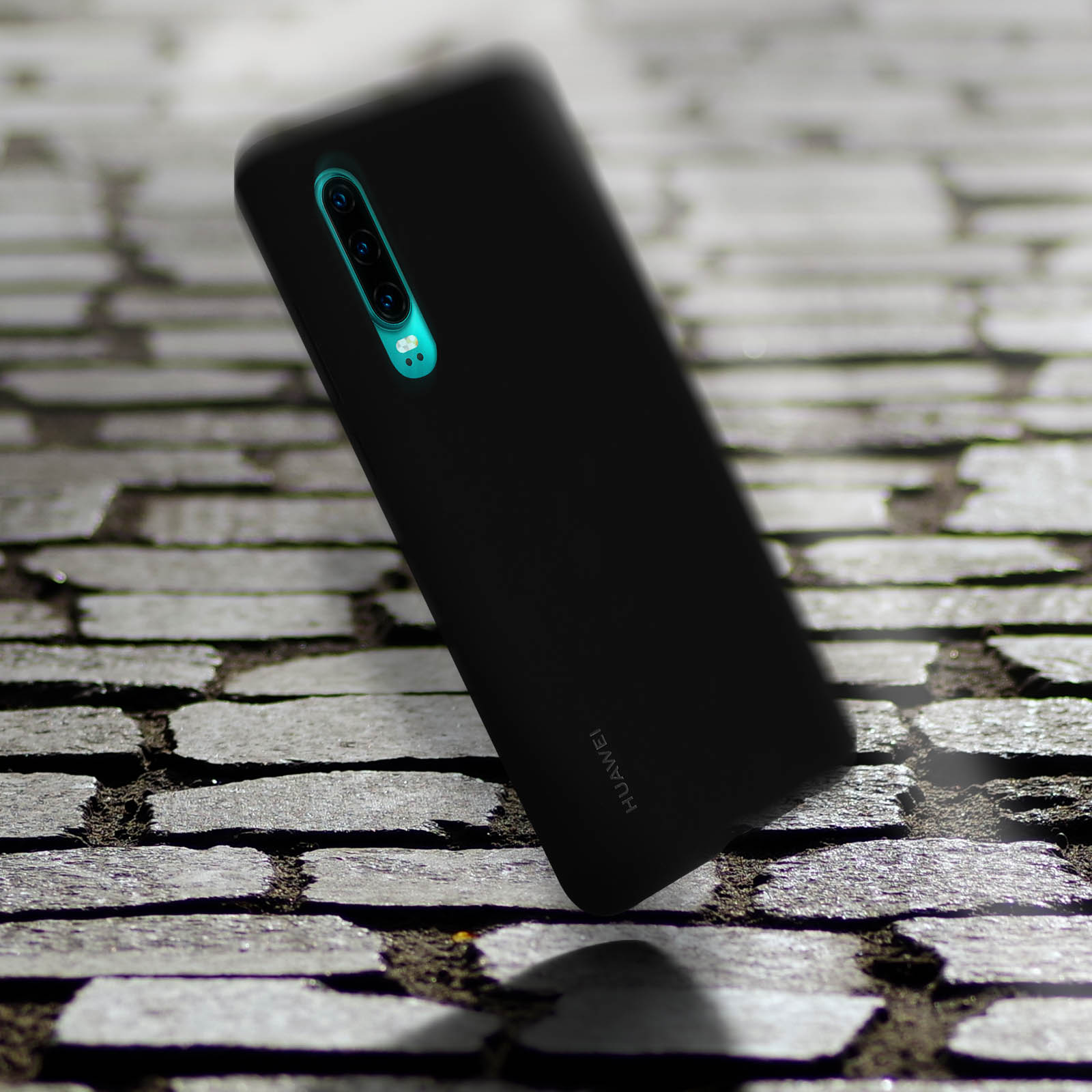 Schwarze Huawei-Handyhülle auf Kopfsteinpflaster. Das Telefon ist leicht angewinkelt.