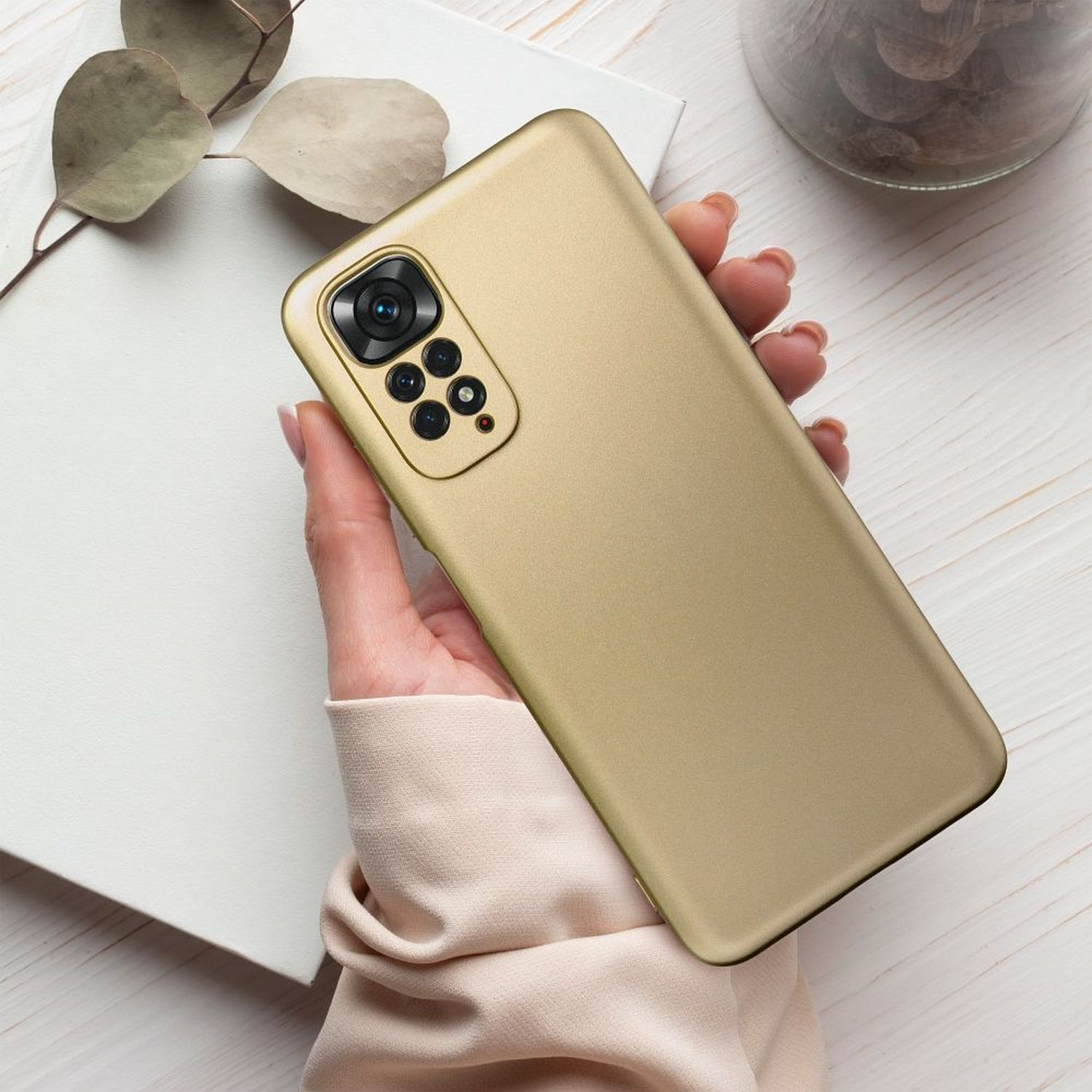 Eine goldene Handyhülle, die von einer Hand gehalten wird. Die Hülle hat mehrere Kameras und eine glatte Oberfläche.