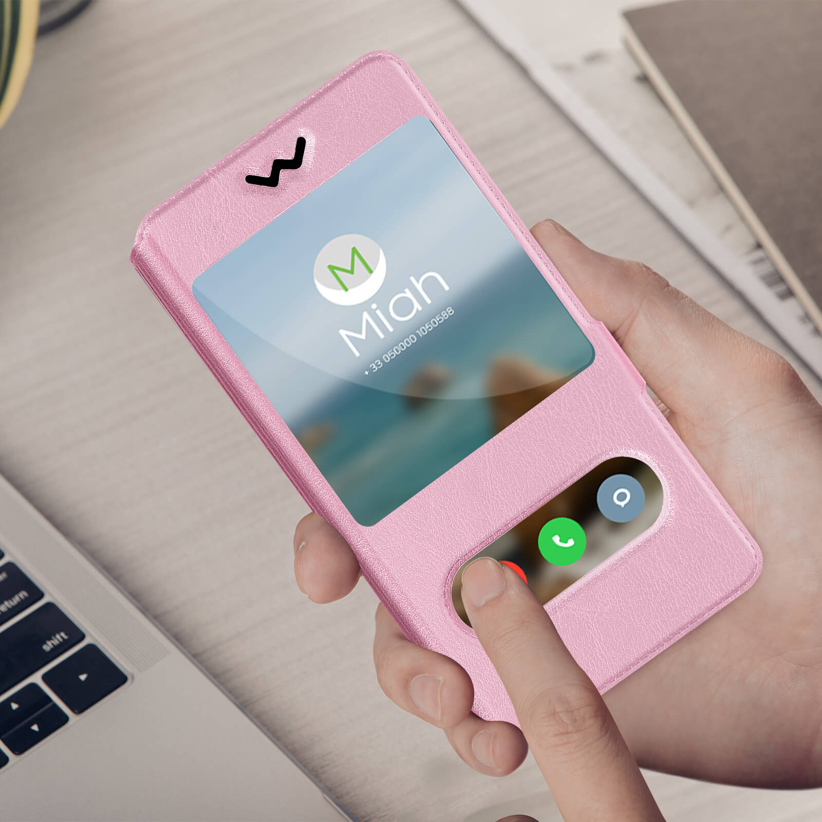 Coque de téléphone rose avec écran affichant un appel, main touchant l'écran et un ordinateur portable.