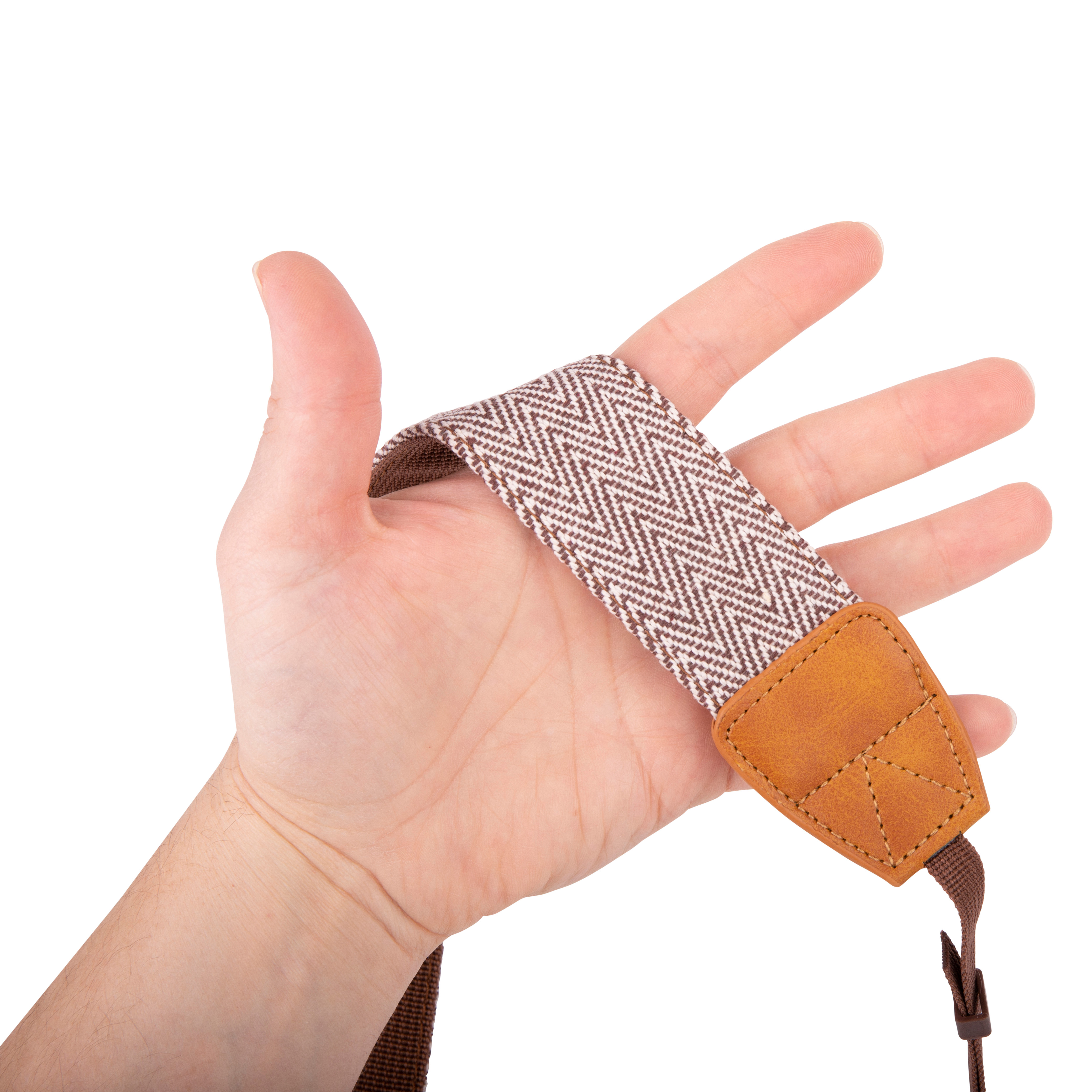 Eine Hand, die einen Kameragurt hält. Der Gurt ist braun und weiß mit Fischgrätmuster.