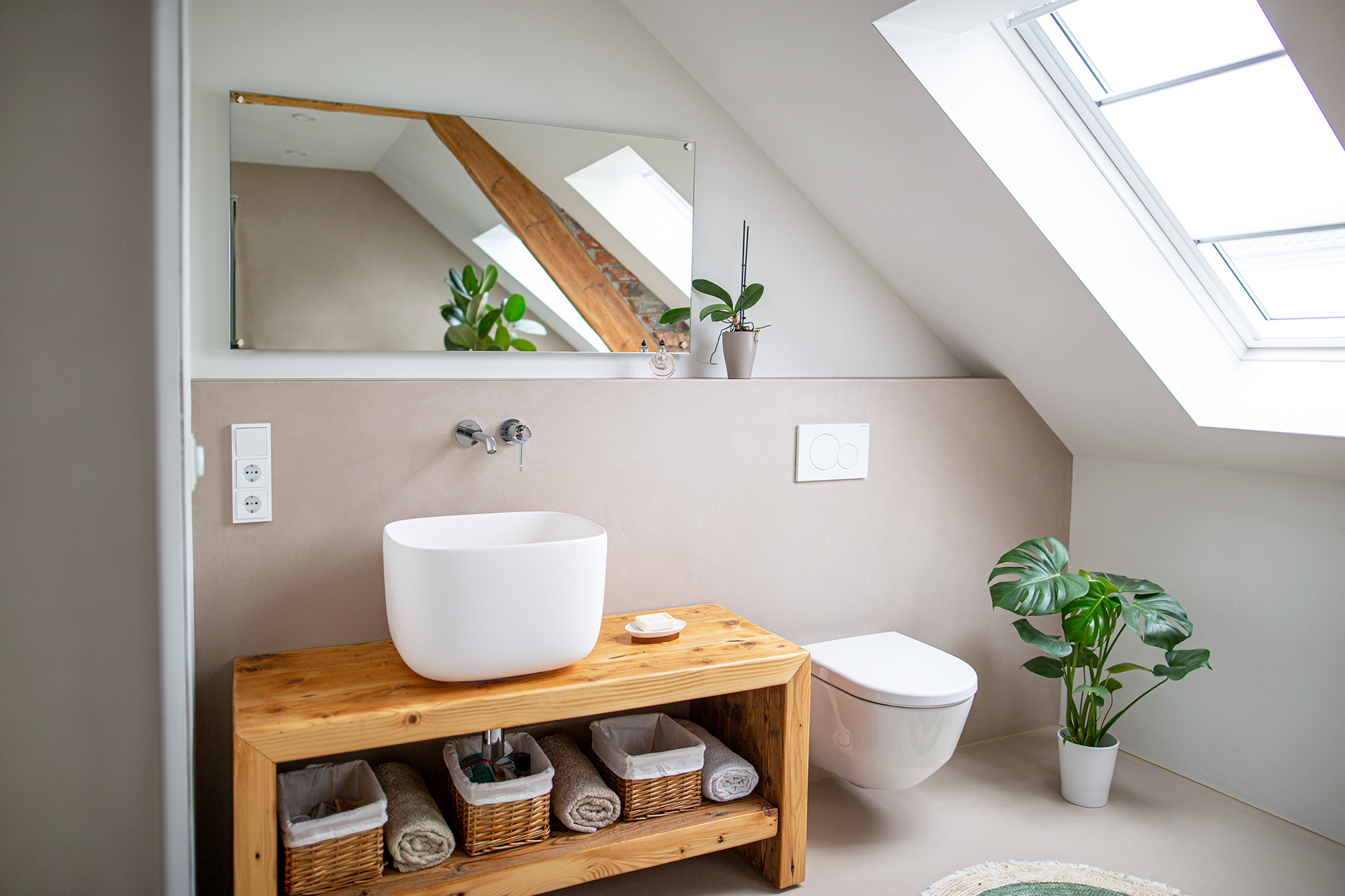 Badezimmer mit weißem Waschbecken, Toilette und Holzschrank. Pflanzen und Spiegel vorhanden.