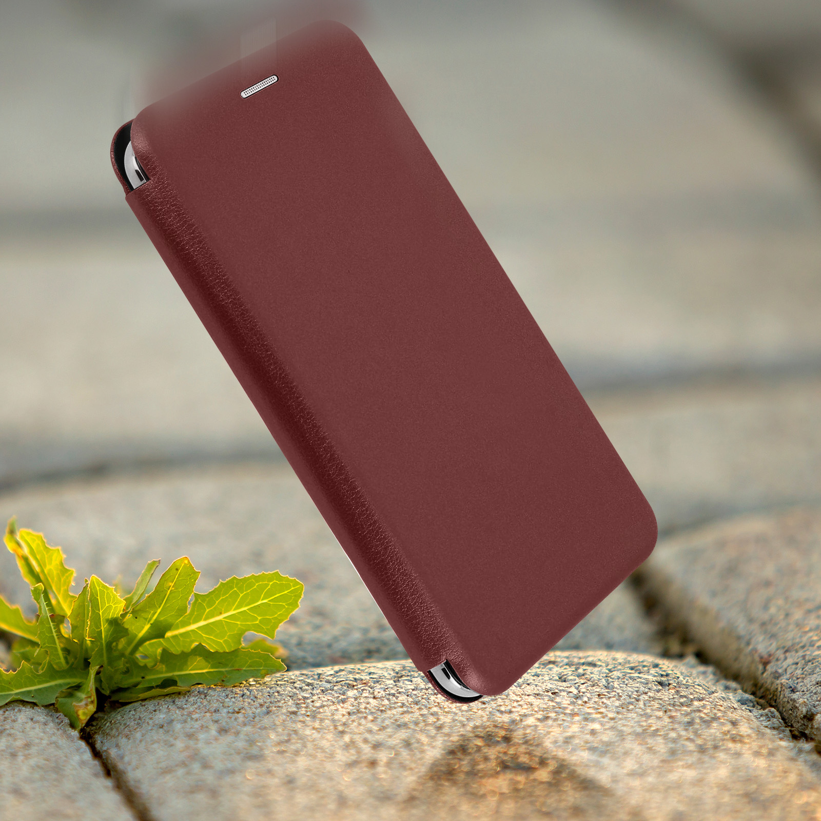 Custodia per telefono rosso scuro fluttuante, con pietra e pianta verde sullo sfondo.