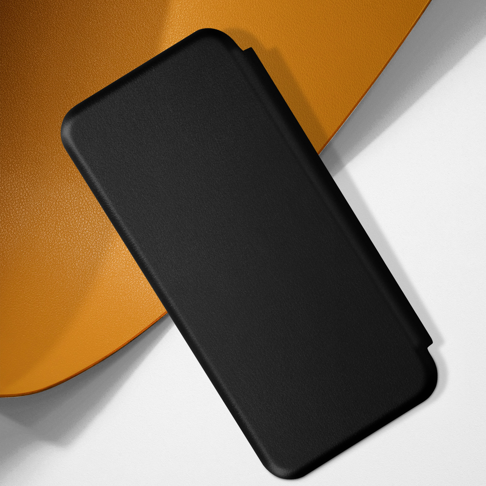 Custodia per telefono nera, texture in pelle, su una superficie arancione e bianca.