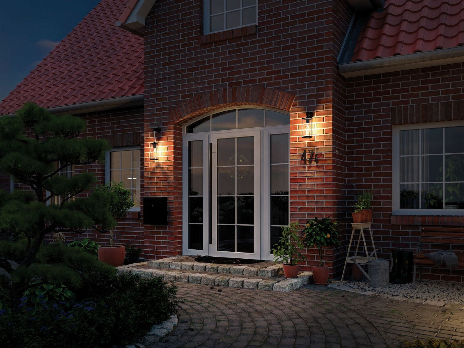 Wejście do domu w nocy, ceglana fasada, zapalone światła.