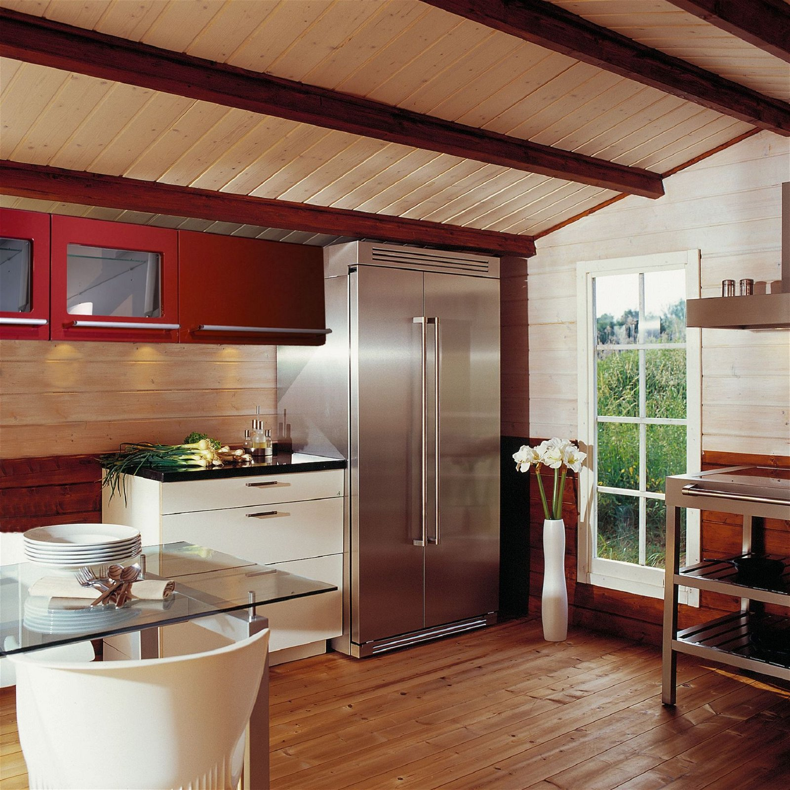 Una cucina con soffitto in legno, armadi rossi ed elettrodomestici in acciaio inossidabile.