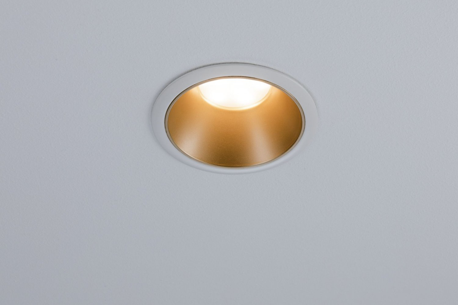 Una luce da incasso a soffitto con cornice bianca e superficie interna dorata.