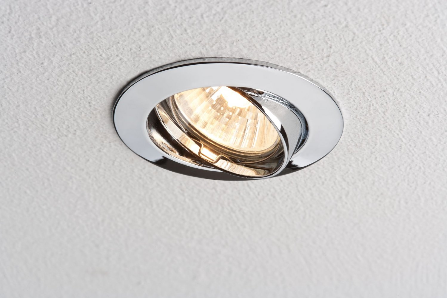 Una luce da soffitto a incasso cromata, angolata verso lo spettatore.
