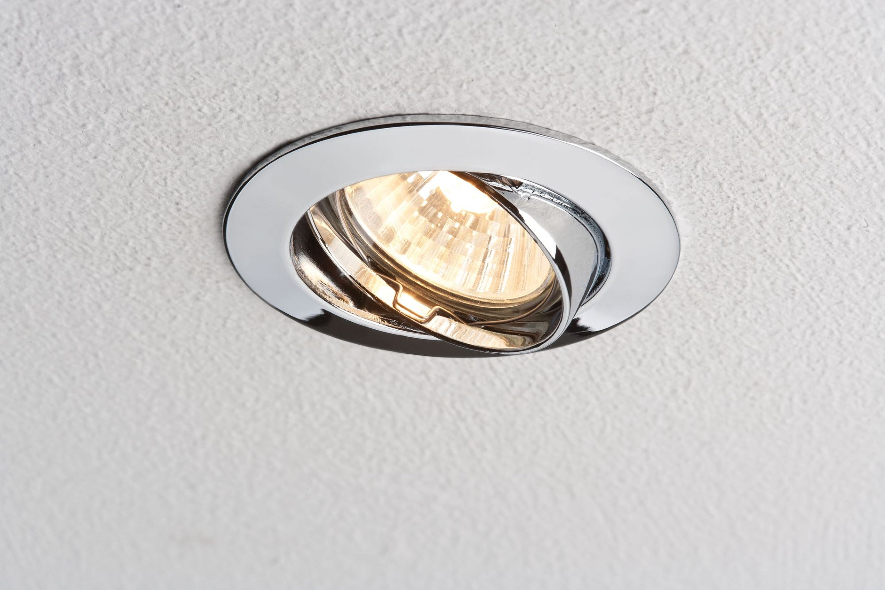 Faretto da incasso cromato. Lampadina accesa all'interno, su sfondo bianco.