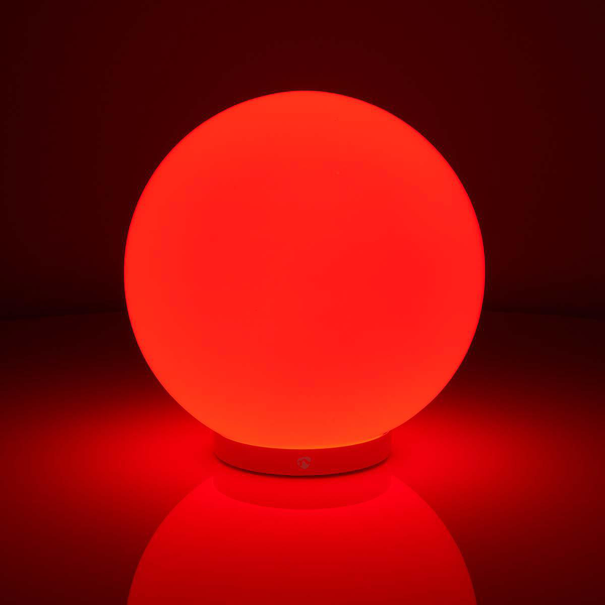 Lampada a sfera rossa brillante su sfondo scuro, riflettendo la luce sulla superficie.