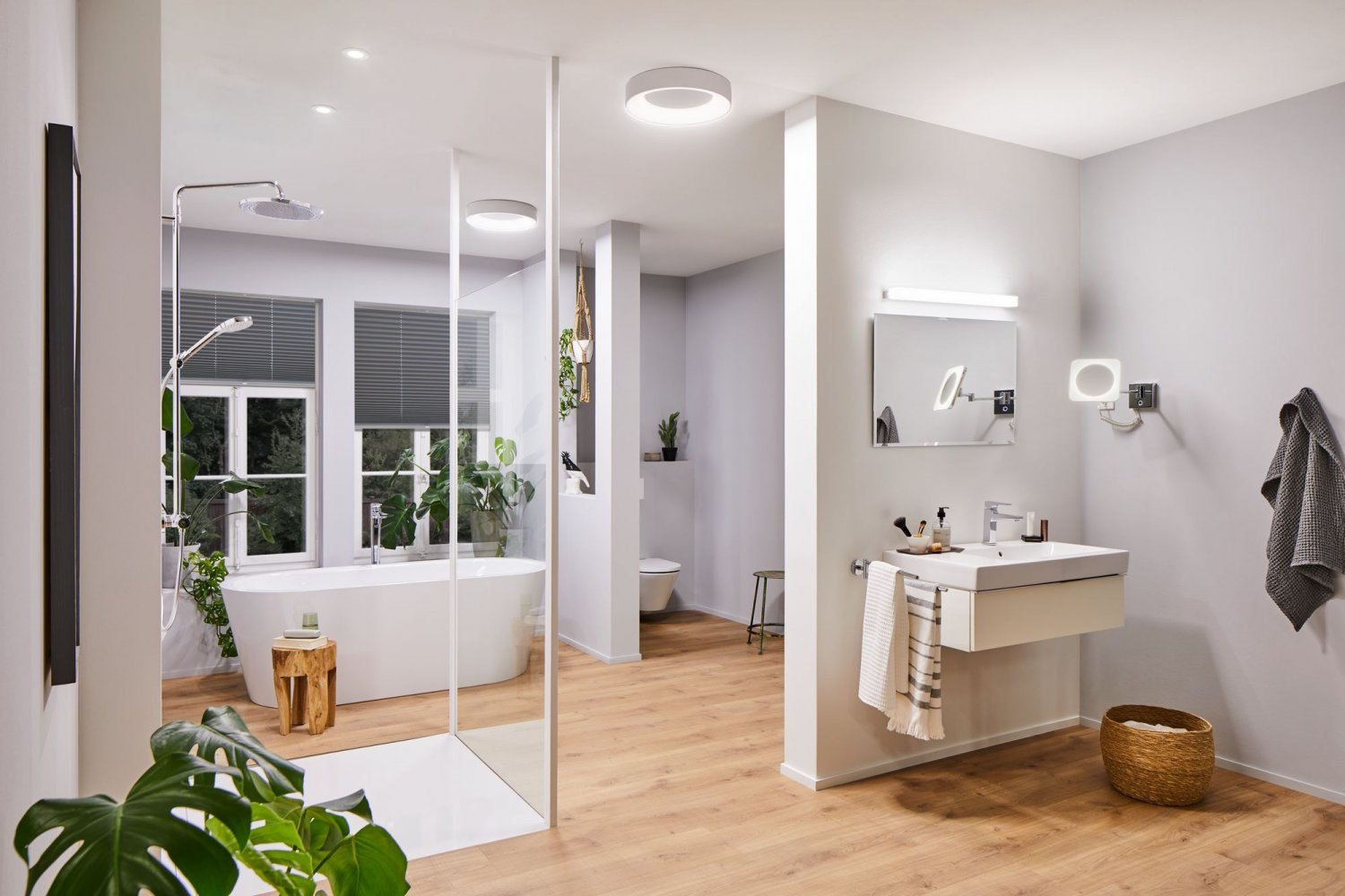 Ein modernes Badezimmer mit Badewanne, Waschbecken und Pflanzen, Holzboden.
