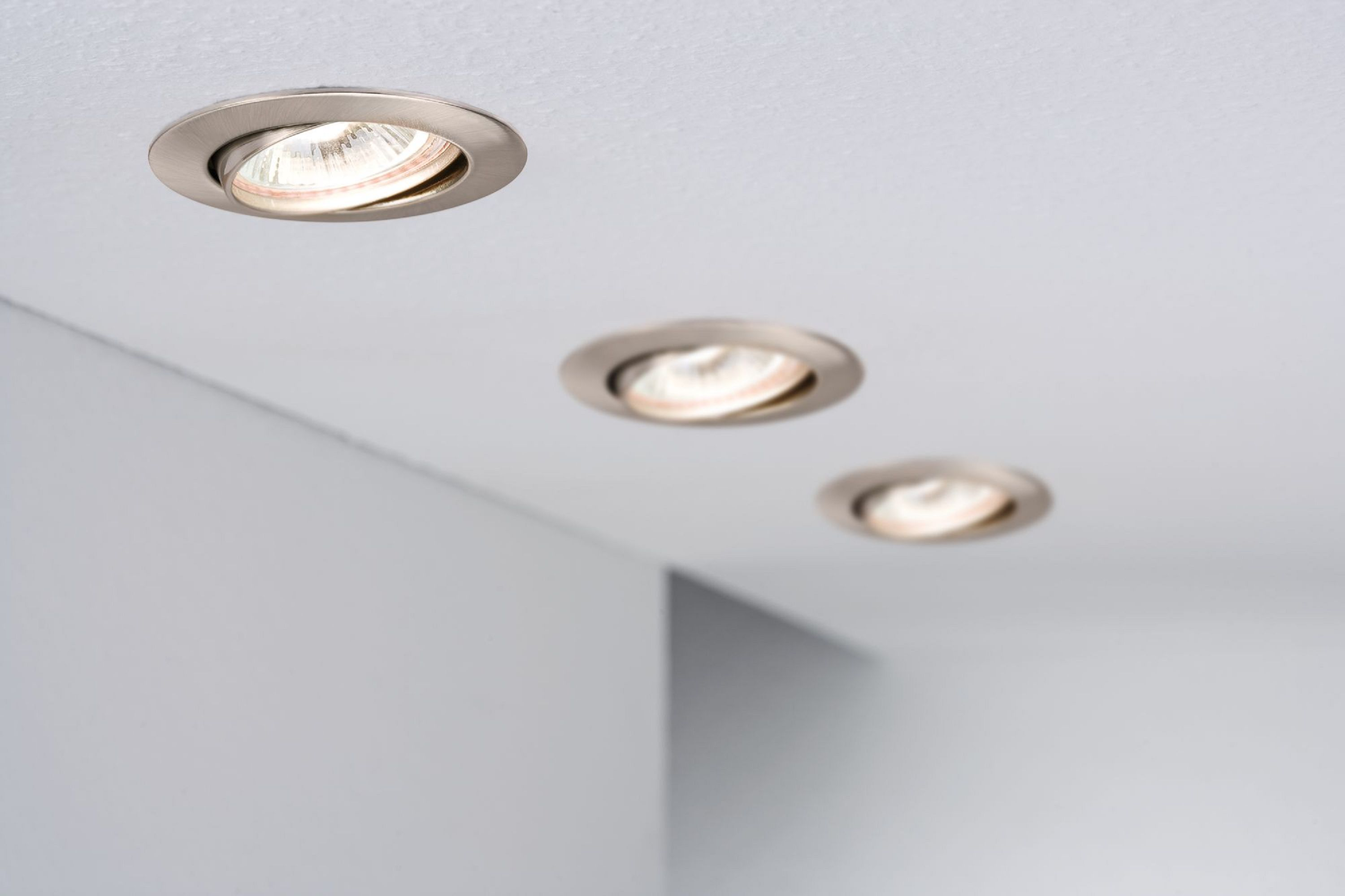 Tre luci a soffitto ad incasso, angolate verso l'osservatore. Le luci sono argentate e luminose.