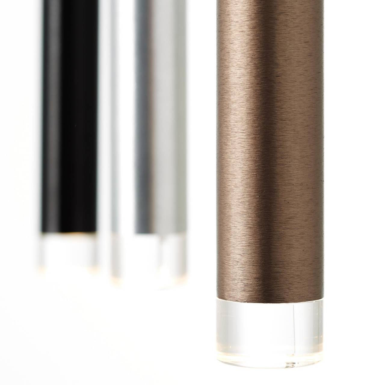 Drei zylindrische Objekte in Bronze, Silber und Schwarz mit transparenten Böden.