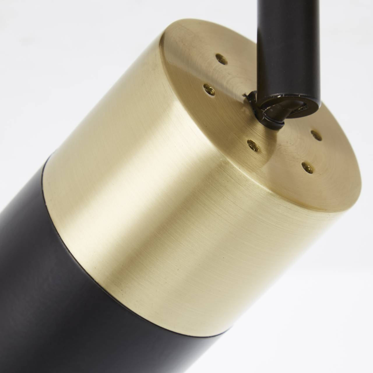 Zylinderförmige Lampe mit schwarzem und messingfarbenem Teil, auf weißem Hintergrund.