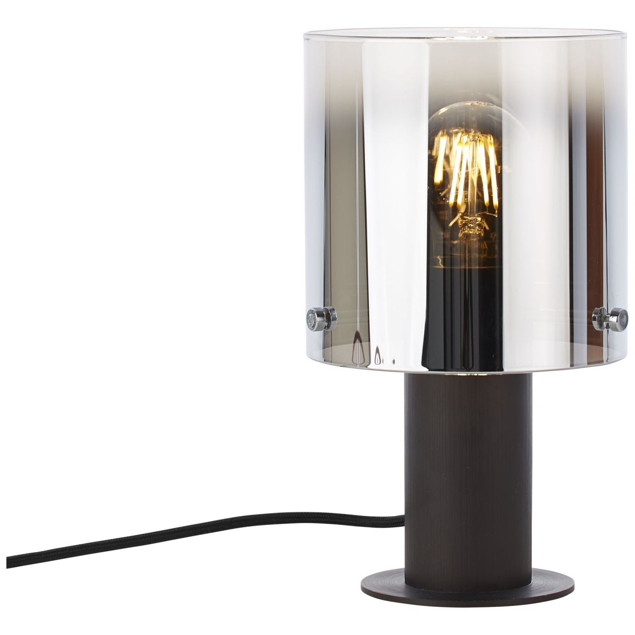 Eine dunkle Tischlampe mit einem zylindrischen Glaslampenschirm und sichtbarer Glühbirne.