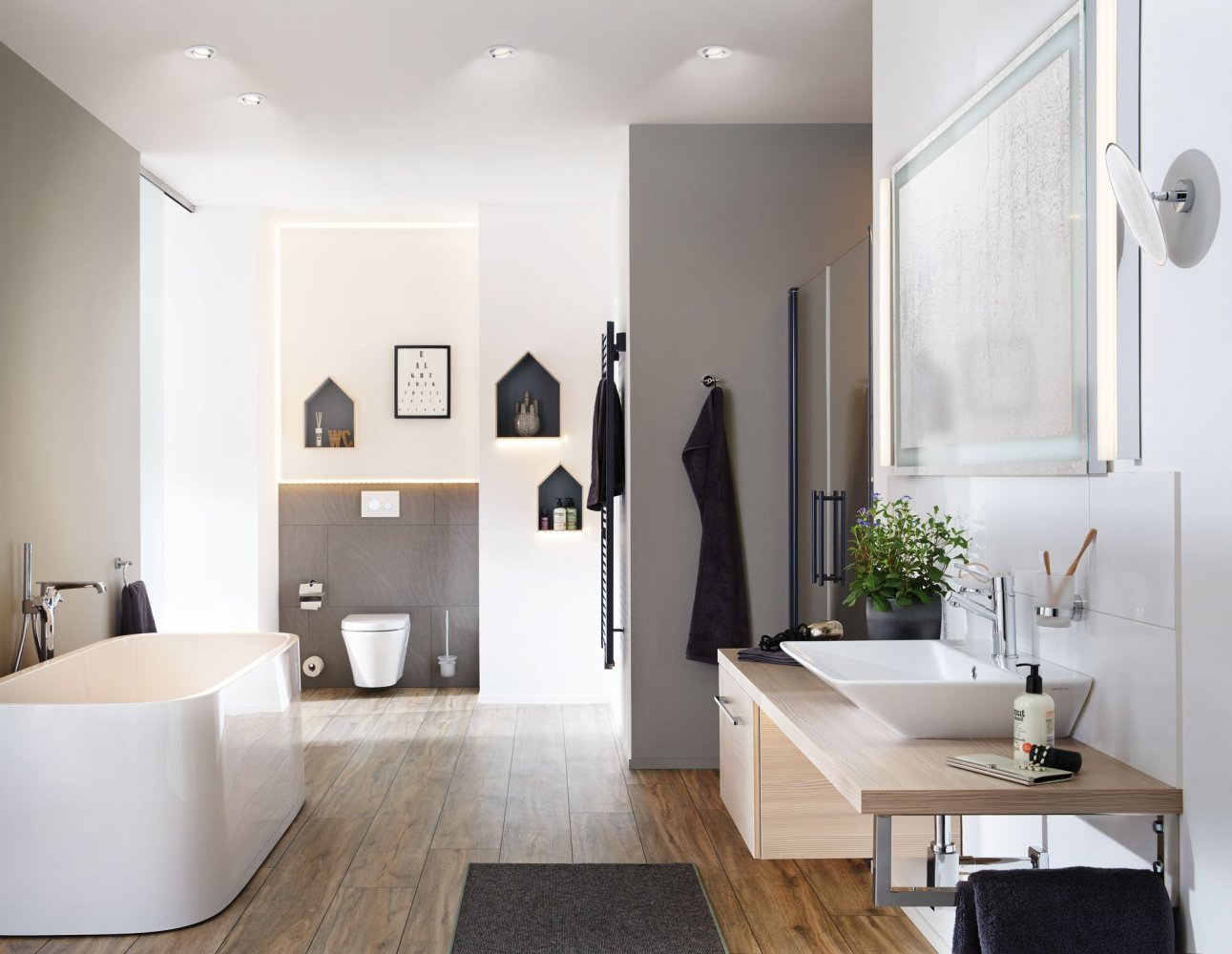 Viene mostrato un bagno moderno con vasca da bagno, lavandino e specchio.