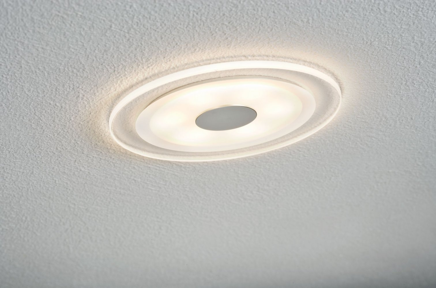 Kreisförmige Deckenleuchte, weiß und beleuchtet, an strukturierter Decke montiert.