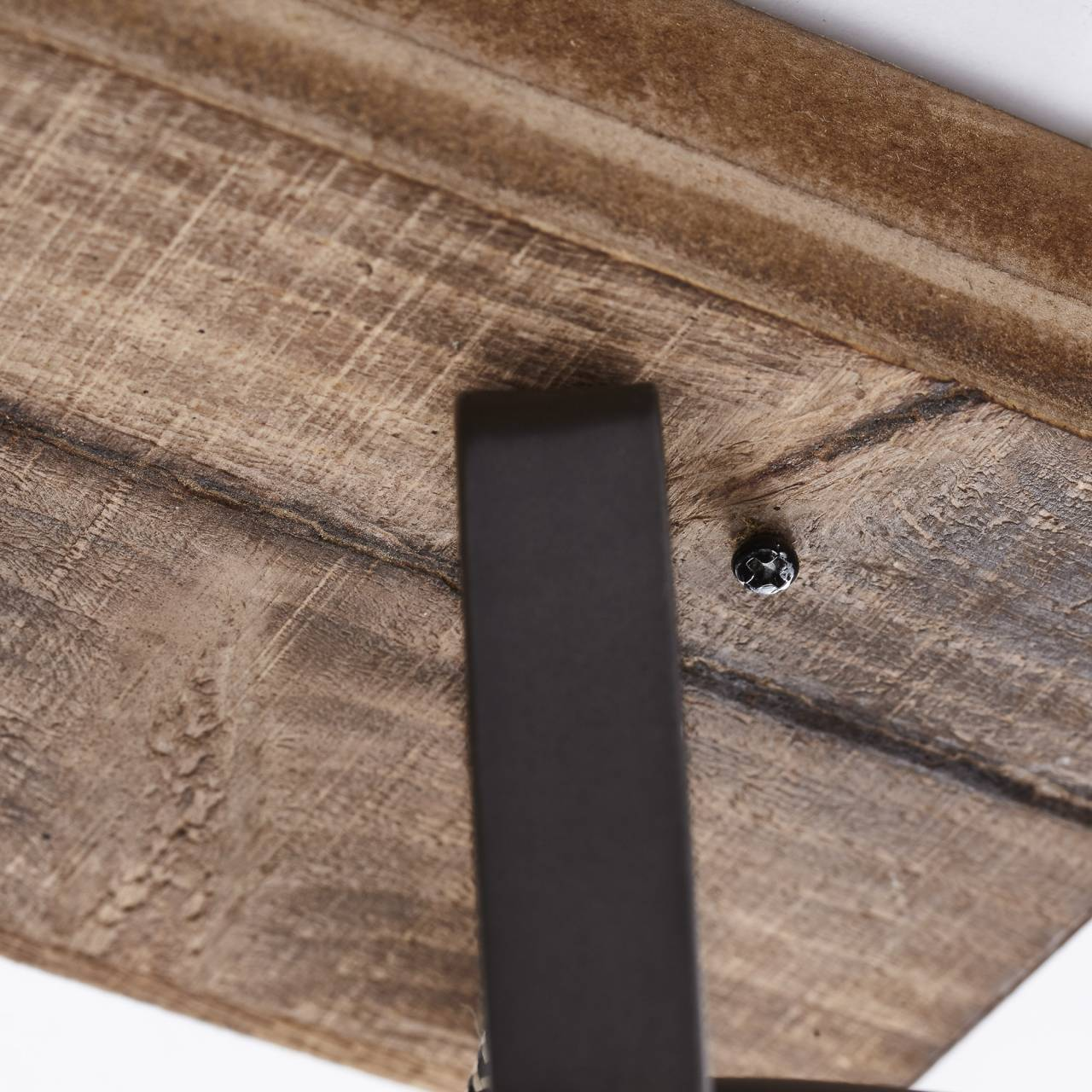 Nahaufnahme von Holzmaserung mit dunklem Metallbein und Schraube.