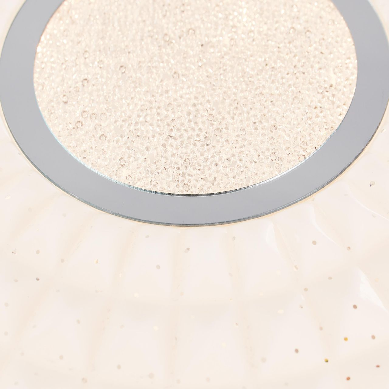 Nahaufnahme einer Lampe mit silbernem Rand und kleinen Kristallen.