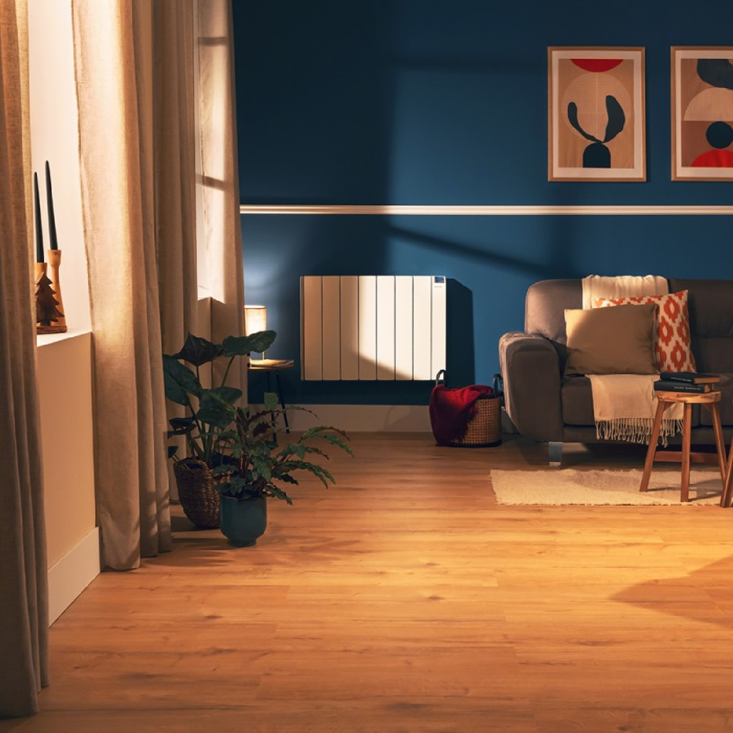 Salon z niebieską ścianą, sofą, roślinami i drewnianą podłogą. Grafika na ścianie, zasłony.