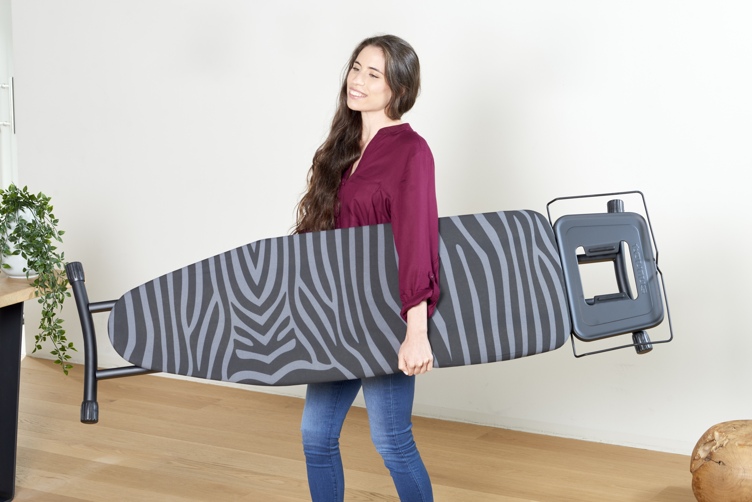 Eine Frau, die ein zusammengeklapptes Bügelbrett mit Zebrastreifen trägt.