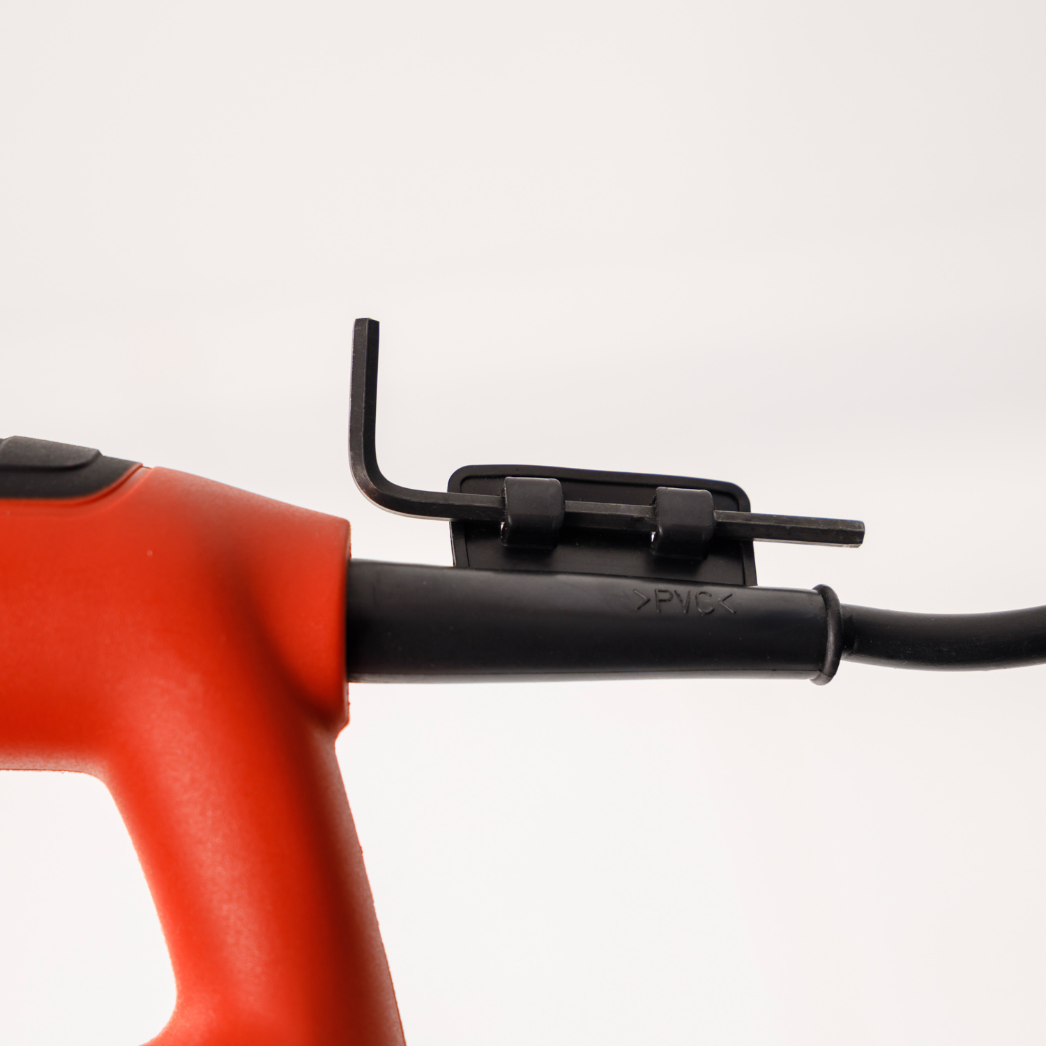 Primer plano de una herramienta eléctrica roja. Tiene un cable negro y un soporte para llave Allen.