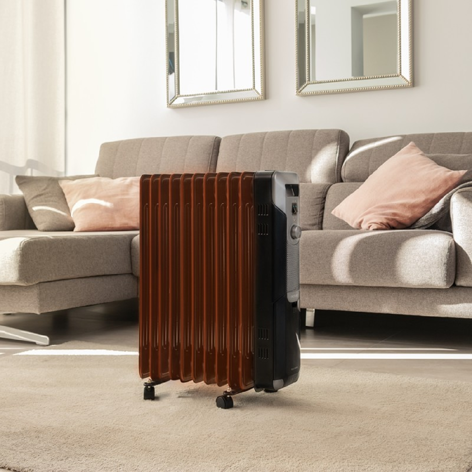 Grzejnik olejowy w pokoju. Brązowy przód, czarny bok. W tle sofa i lustra.