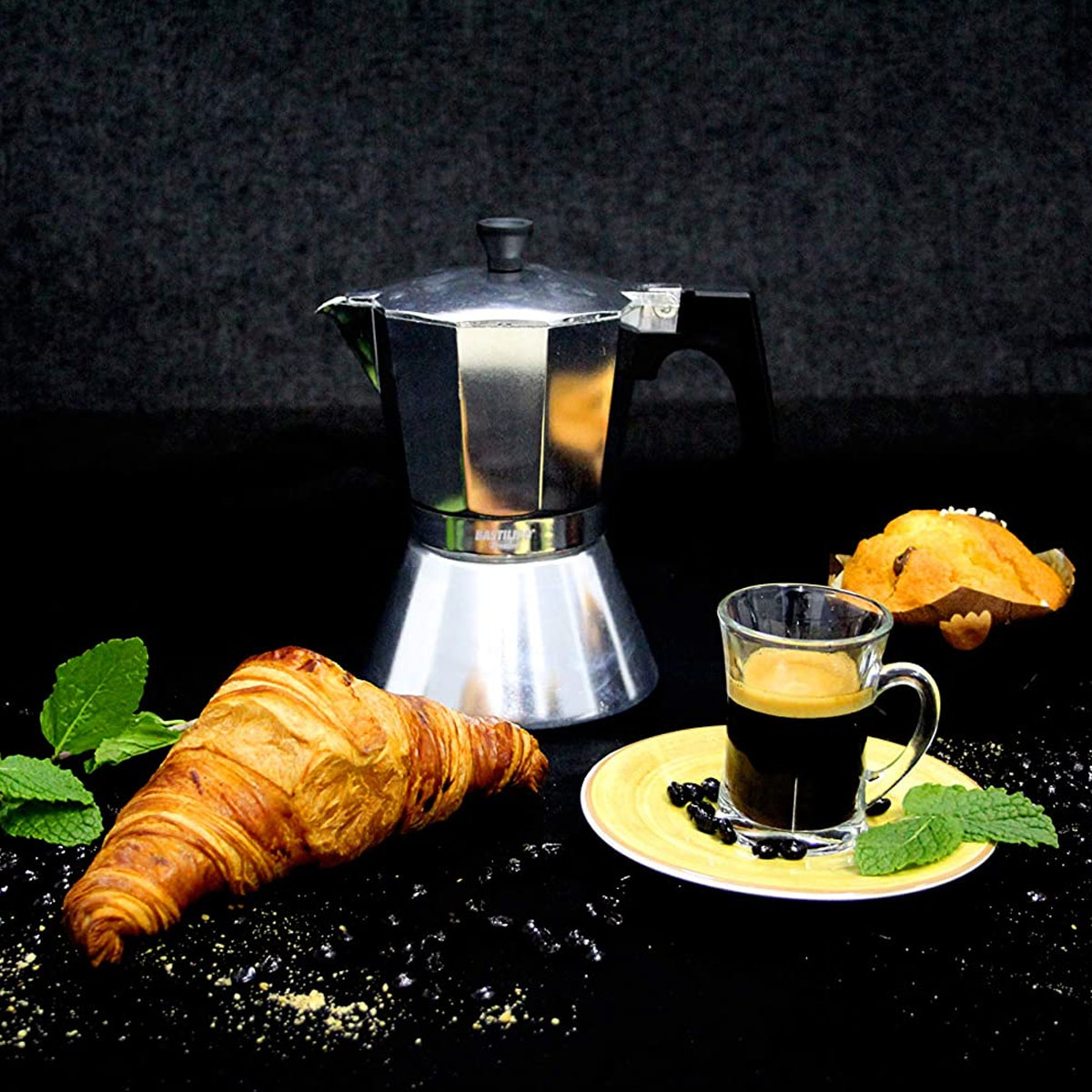Kaffee-Setup mit Mokkakanne, Croissant, Espresso und Muffin.