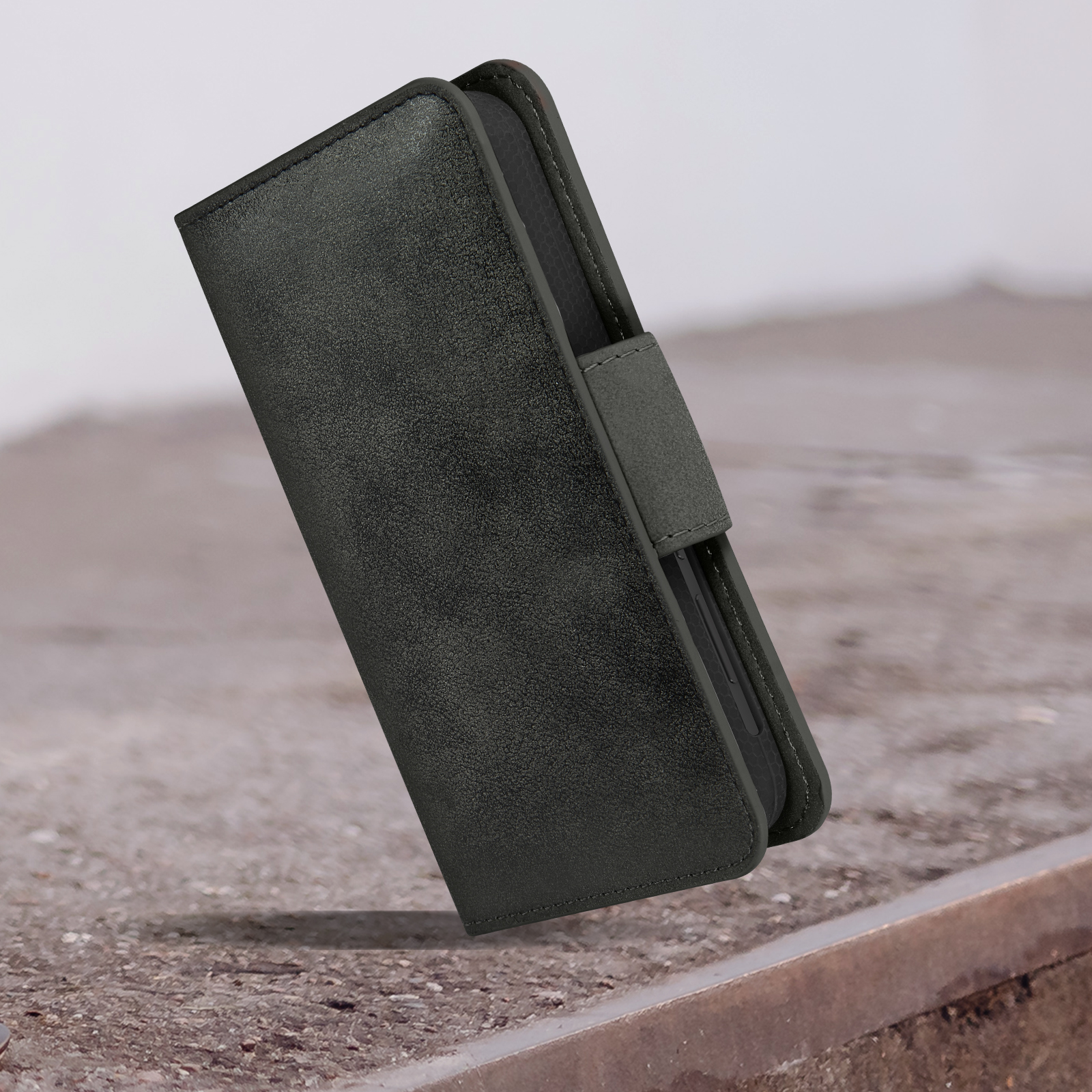 Custodia per telefono nera, chiusa, con texture in pelle. Posizionata su una superficie ruvida.