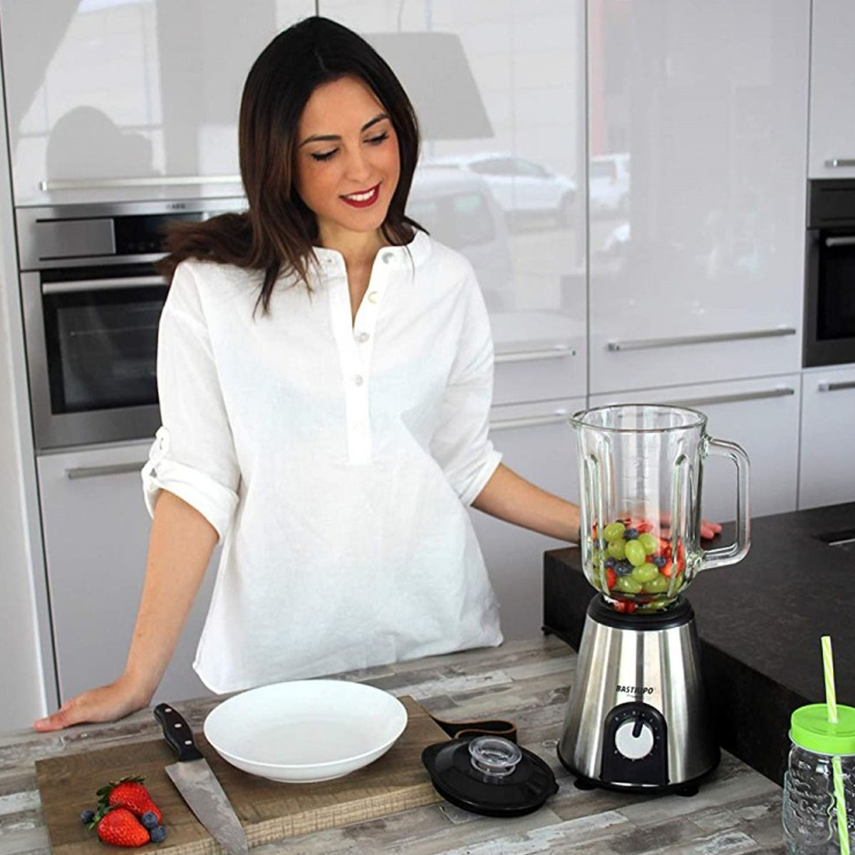 Mujer preparando batido con licuadora. Frutas en la licuadora.