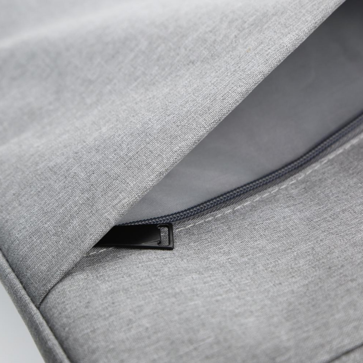 Szara torba na laptopa z częściowo otwartym zamkiem błyskawicznym, odsłaniająca wnętrze.