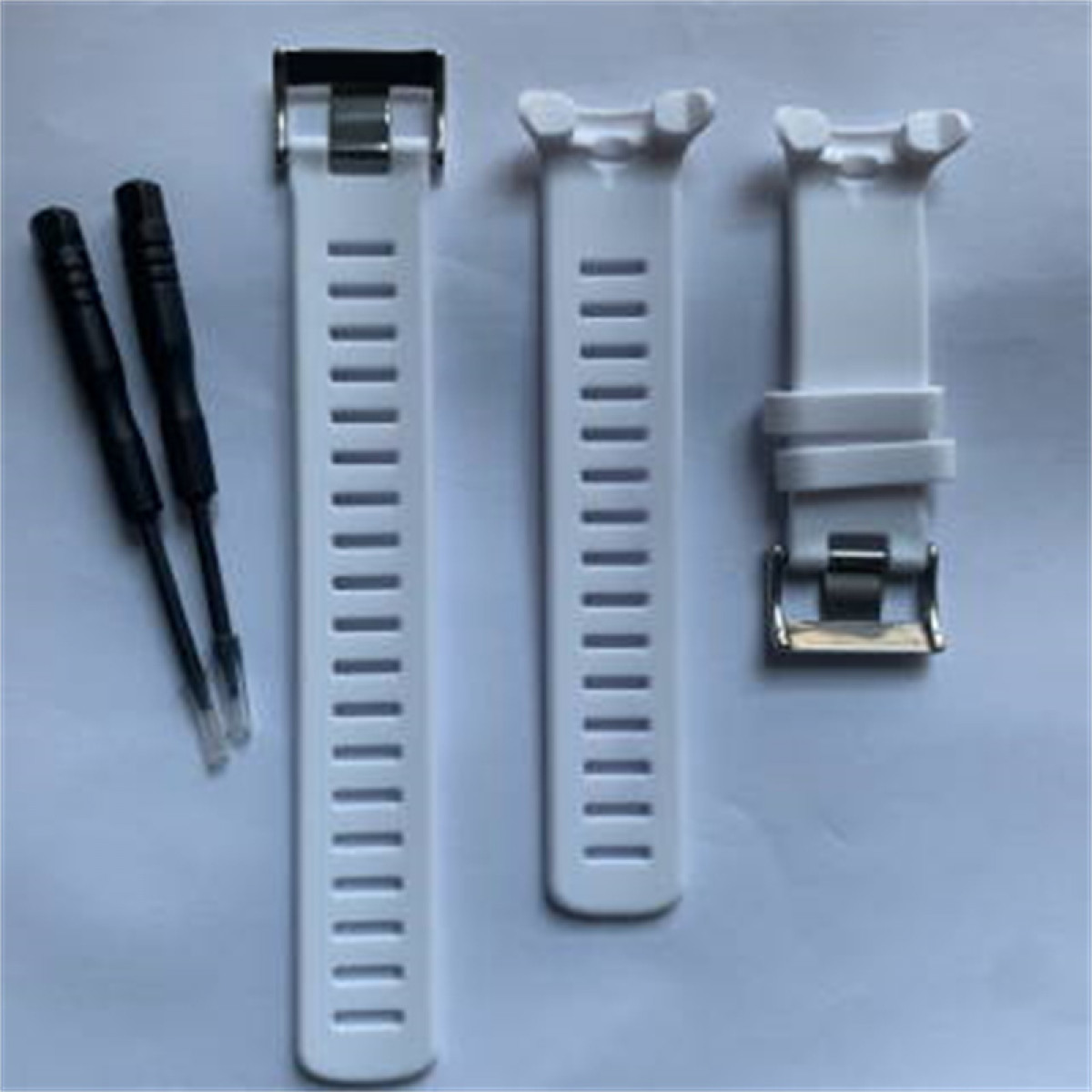 Weiße Uhrenarmbänder, eine Schnalle und ein Satz Schraubendreher liegen auf weißem Untergrund.