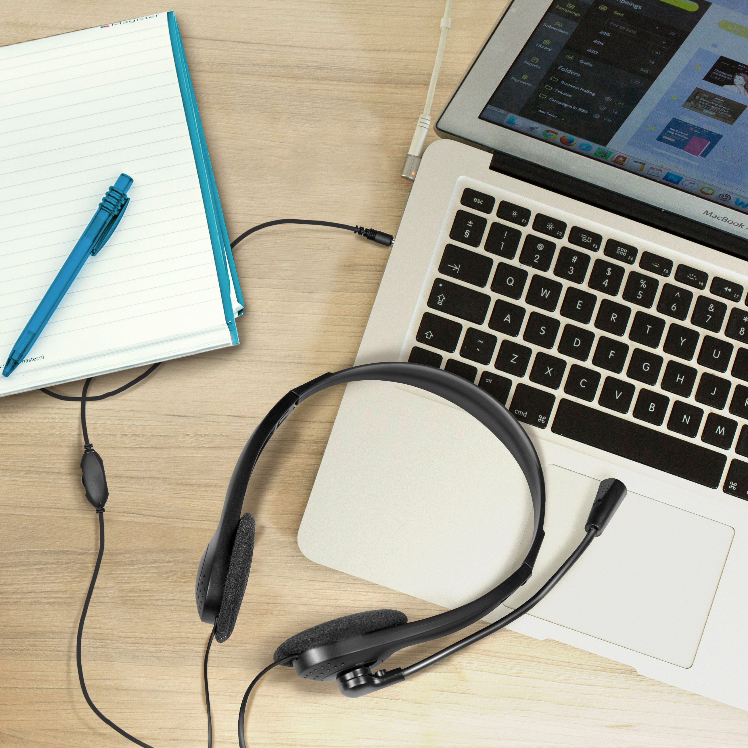 Casque sur un ordinateur portable, avec un carnet et un stylo, vue de dessus.