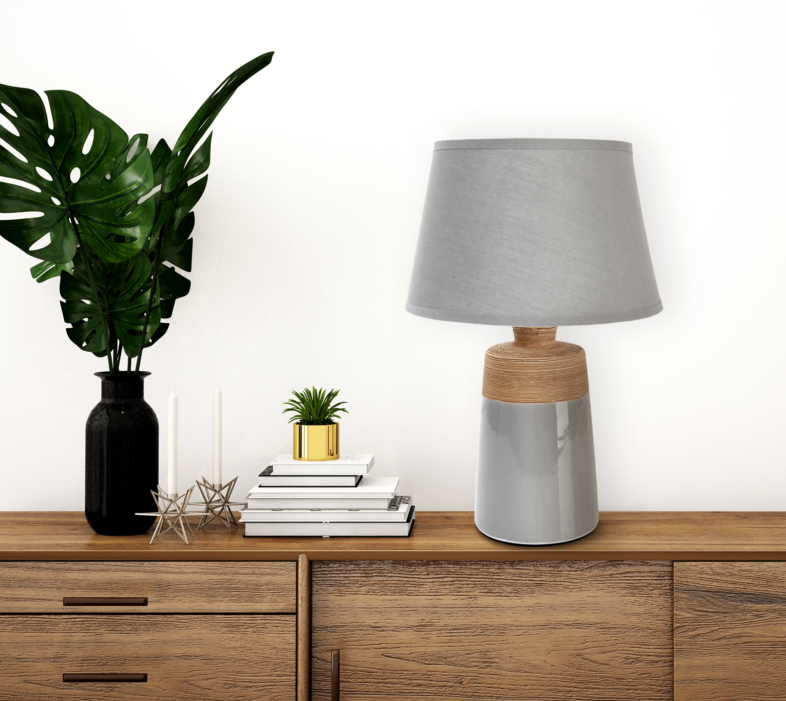 Tischlampe, Pflanzen in schwarzer Vase, Bücher und Kerzen auf Holzoberfläche.