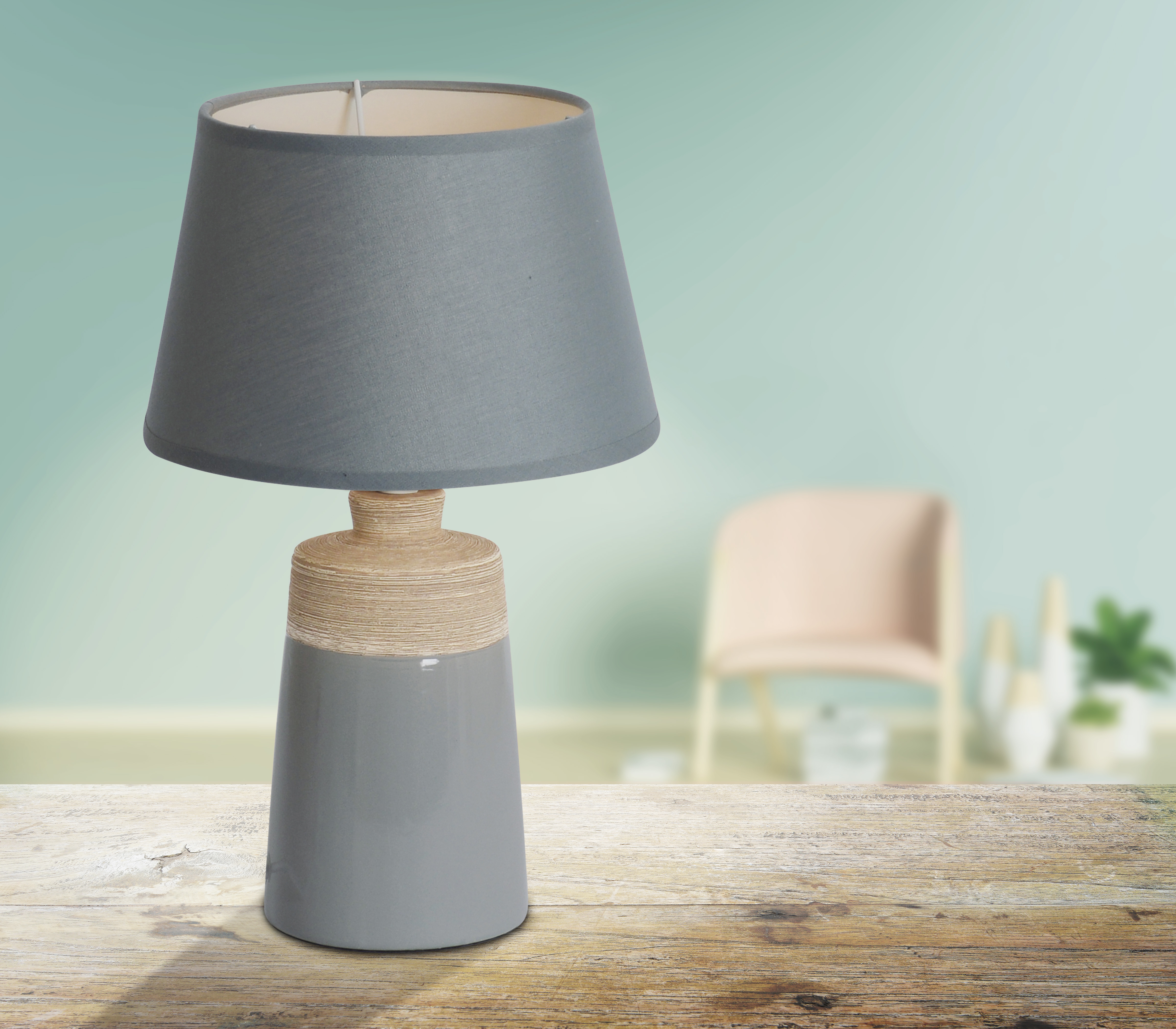 Graue Tischlampe mit grauem Lampenschirm. Holztisch und verschwommener Hintergrund.