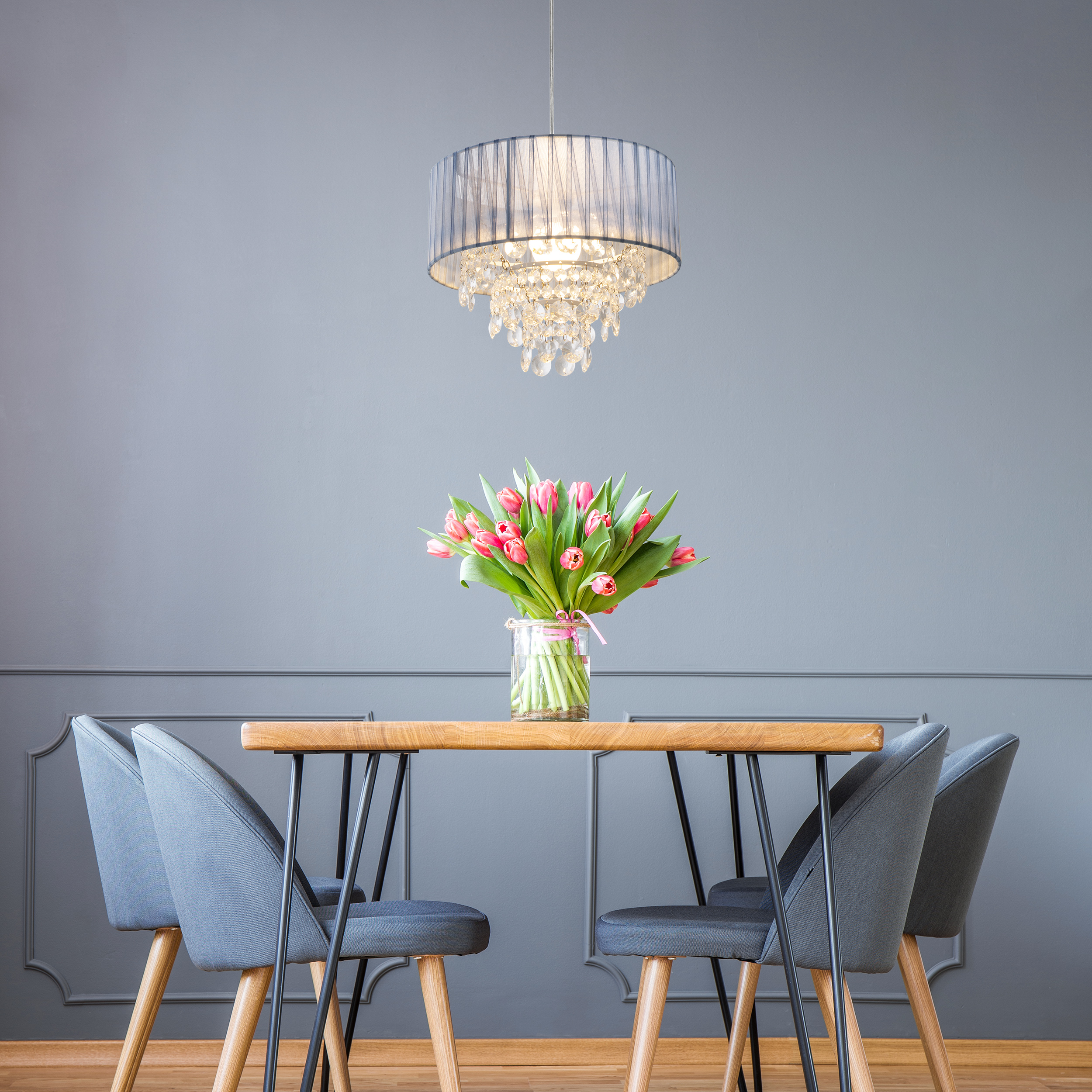 Salle à manger avec table, chaises, lustre et vase de tulipes roses.