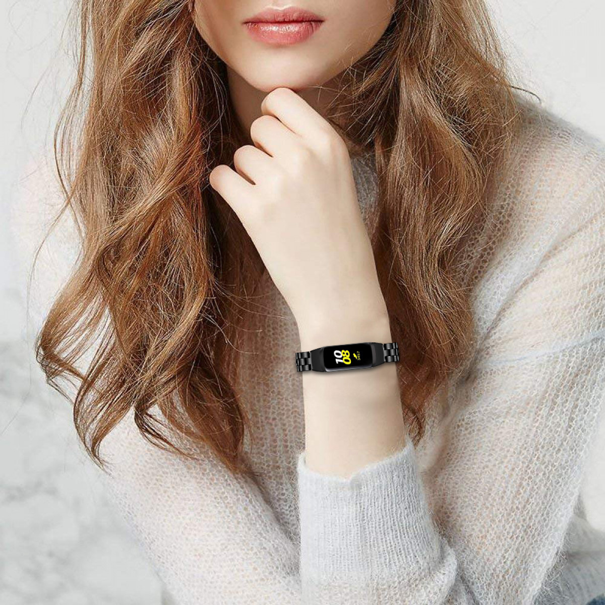 Handgelenk einer Frau mit schwarzem Smart-Armband. Armband zeigt Zahl und Blatt.