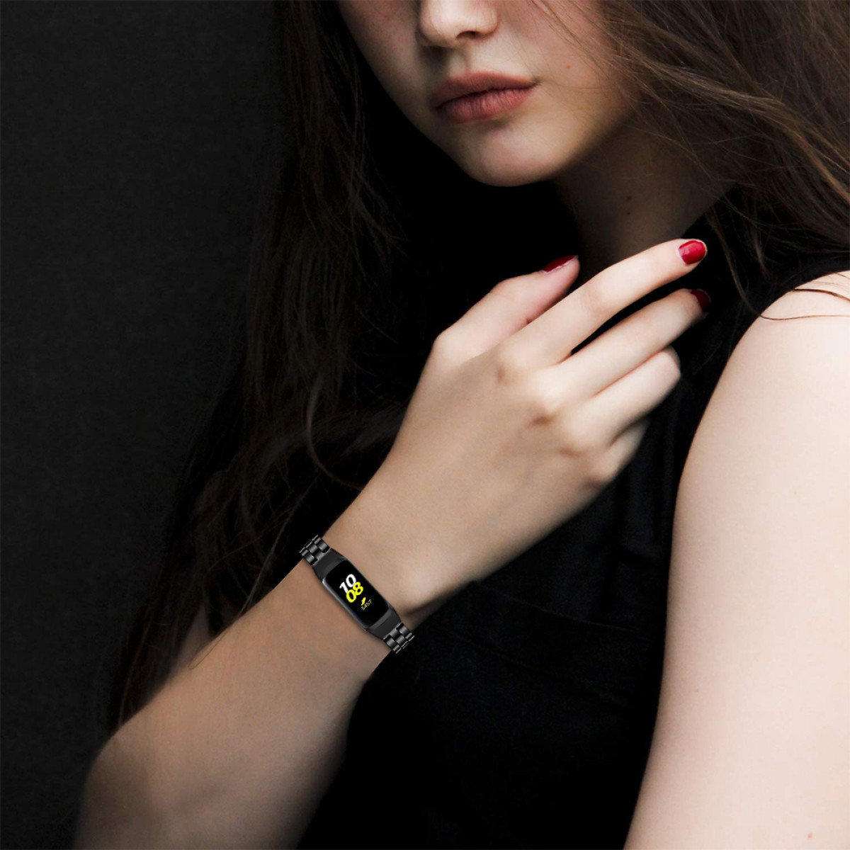 Handgelenk einer Frau mit schwarzem Smartband. Band zeigt Zeit und hat ein Metallband.