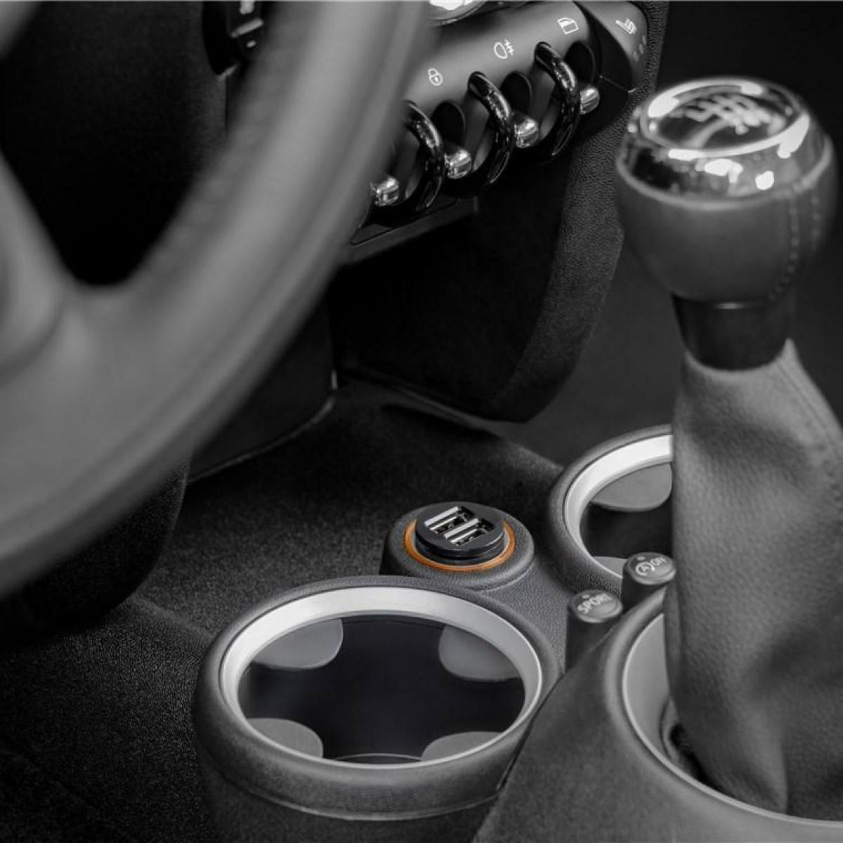 Autointerieur mit USB-Ladegerät in der Mittelkonsole. Becherhalter und Gangschaltung sichtbar.